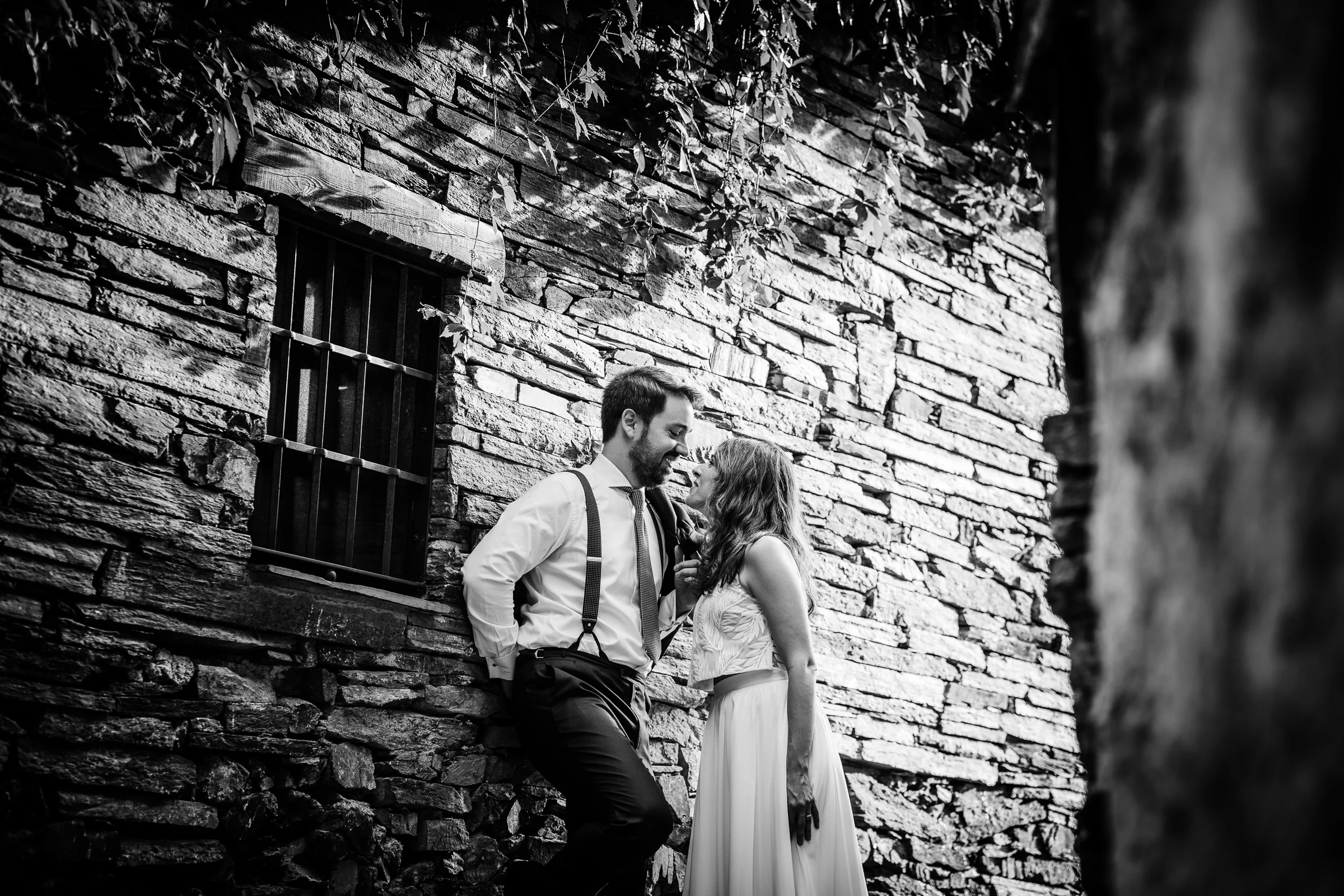 Ainhoa y Fer, retrato en blanco y negro de la pareja junto a un muro de piedra, Madrid