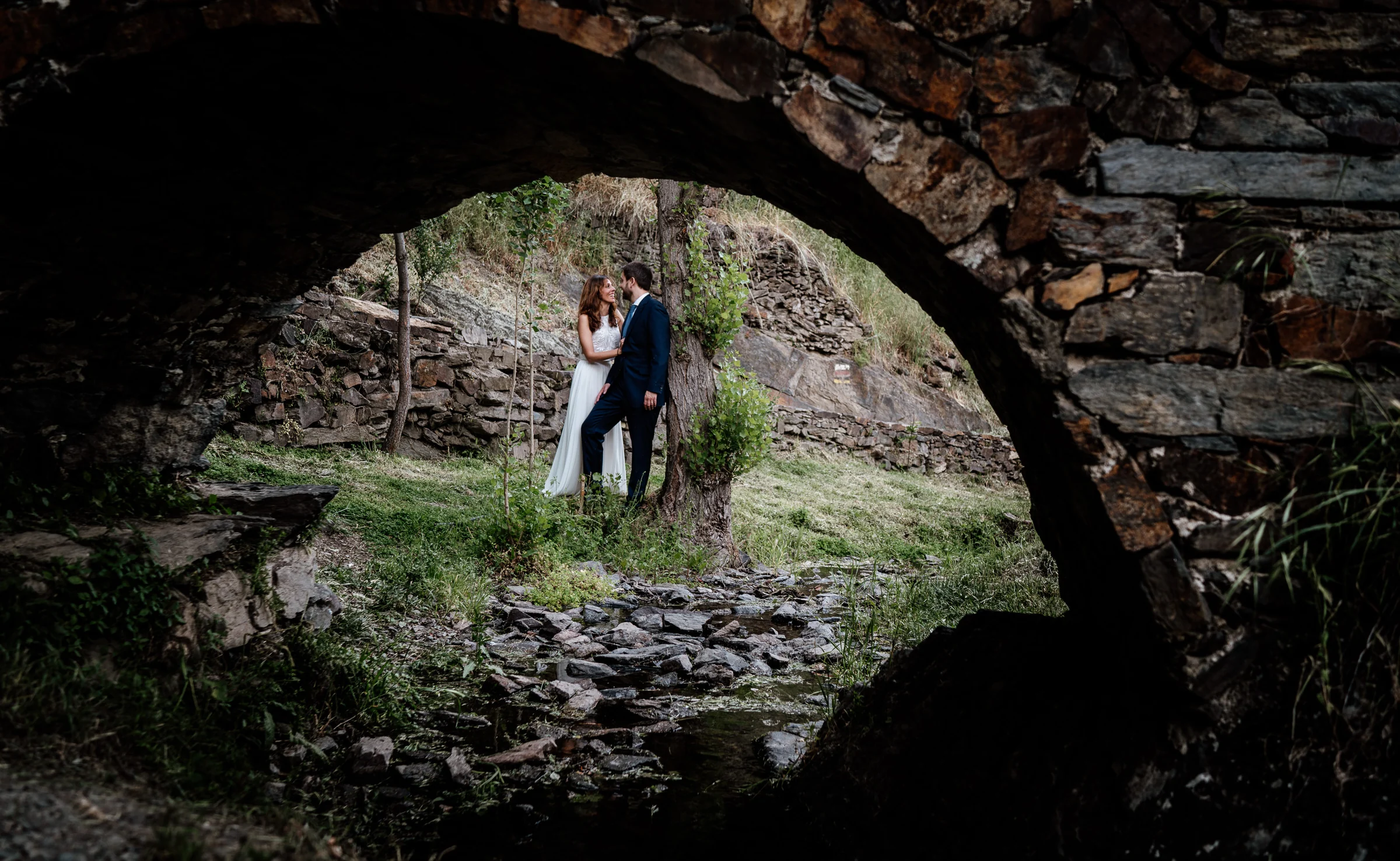 Ainhoa y Fer, retrato de la pareja bajo un puente de piedra y junto al arroyo, Madrid