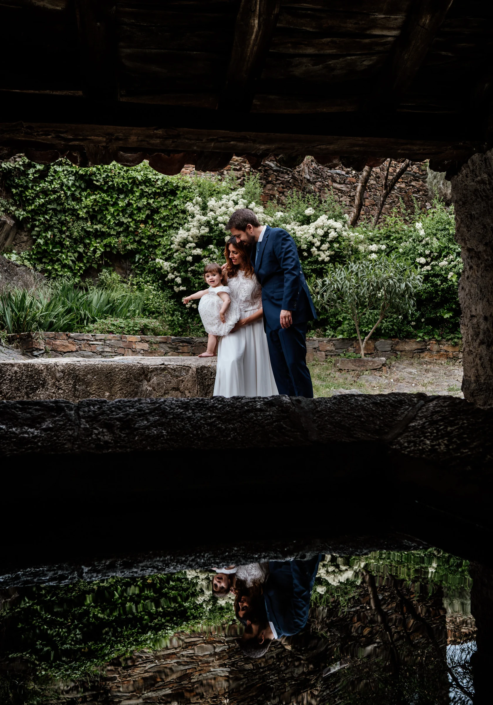Ainhoa y Fer, retrato vertical de la pareja con su hija junto a la fuente, Madrid