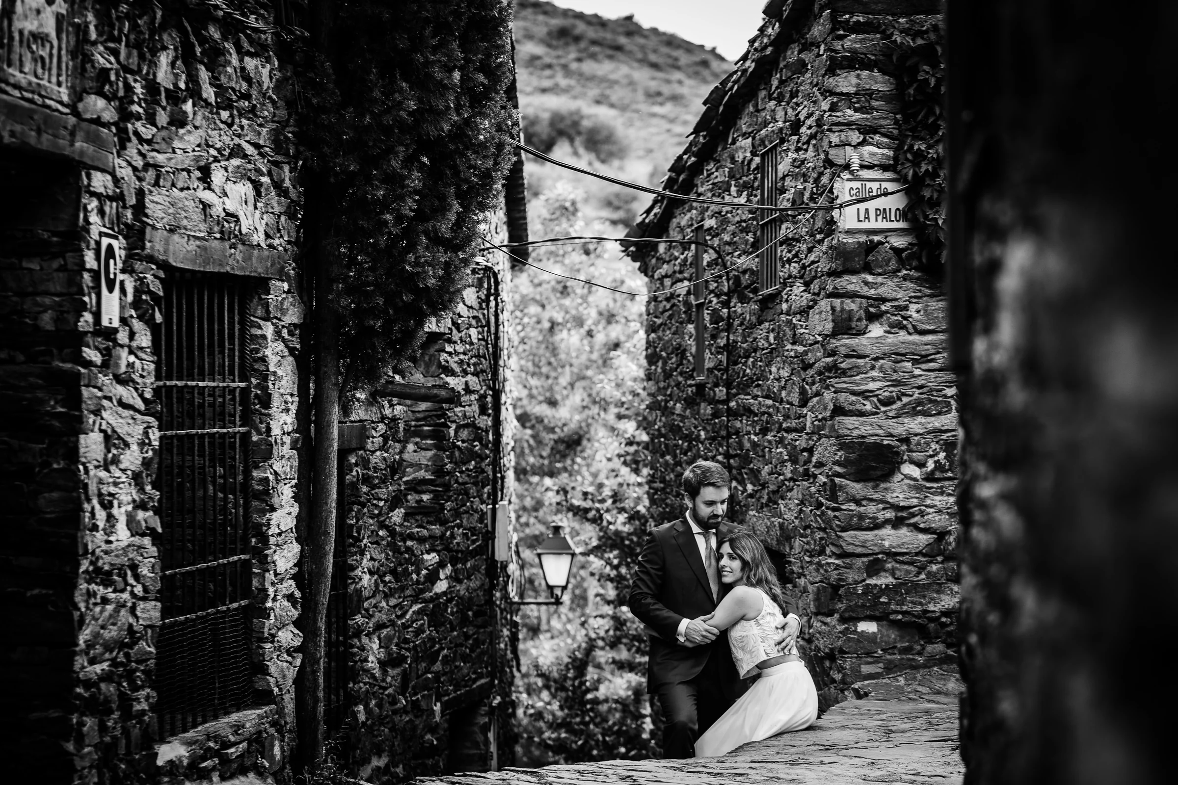 Ainhoa y Fer, retrato en blanco y negro de la pareja sentada en una calle rural, Madrid