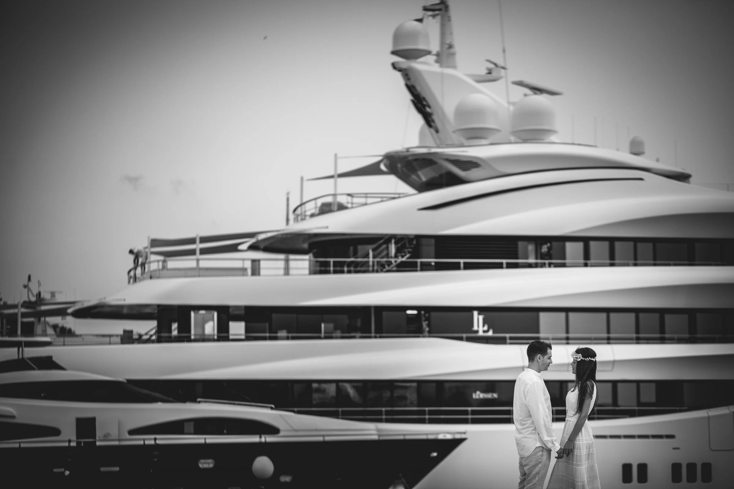 Alba y Jorge junto a un yate en el puerto en blanco y negro, postboda de Alba y Jorge en Ibiza fotografiada por Pedro Zamorano.
