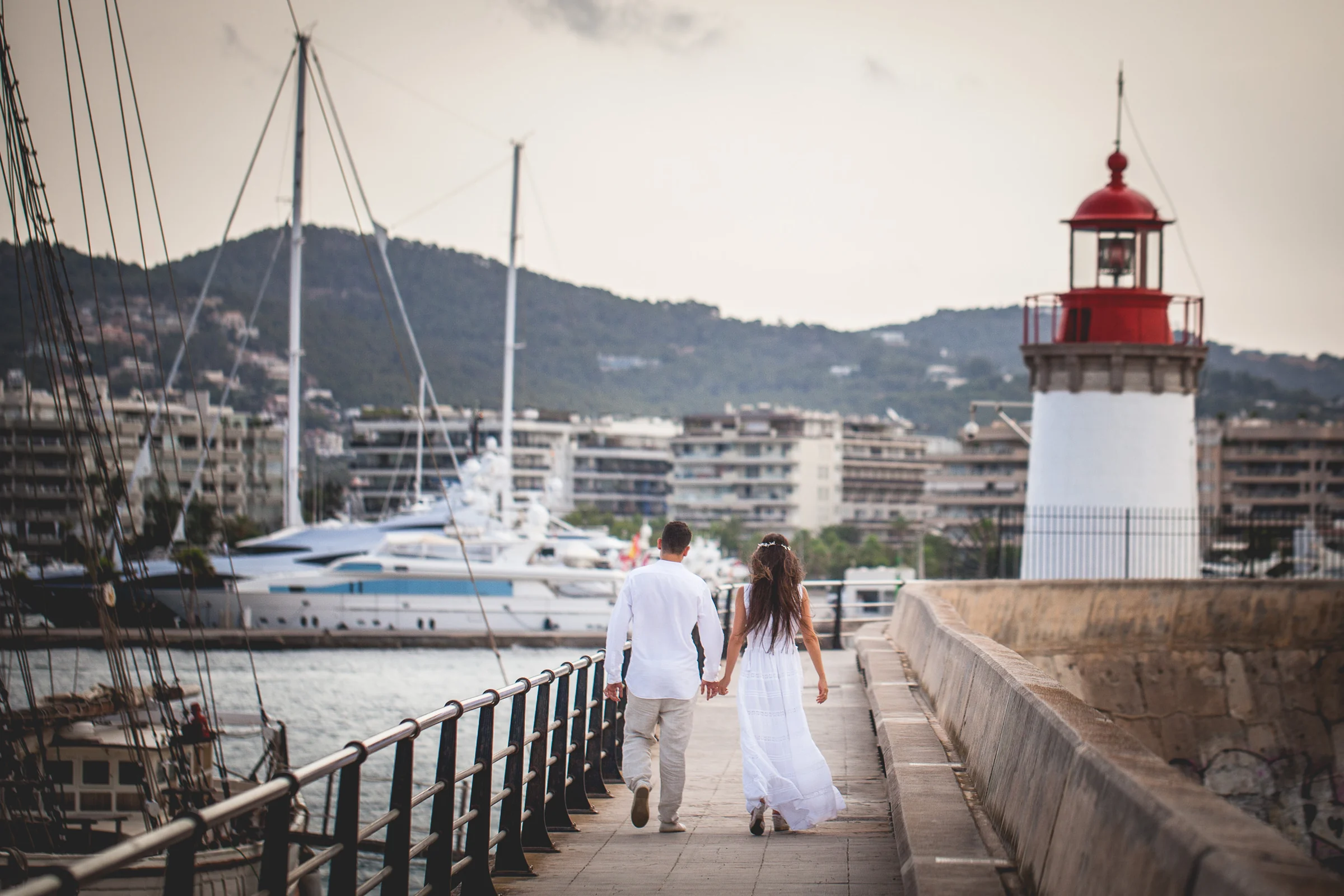 Alba y Jorge paseando junto al faro del puerto, postboda de Alba y Jorge en Ibiza fotografiada por Pedro Zamorano.