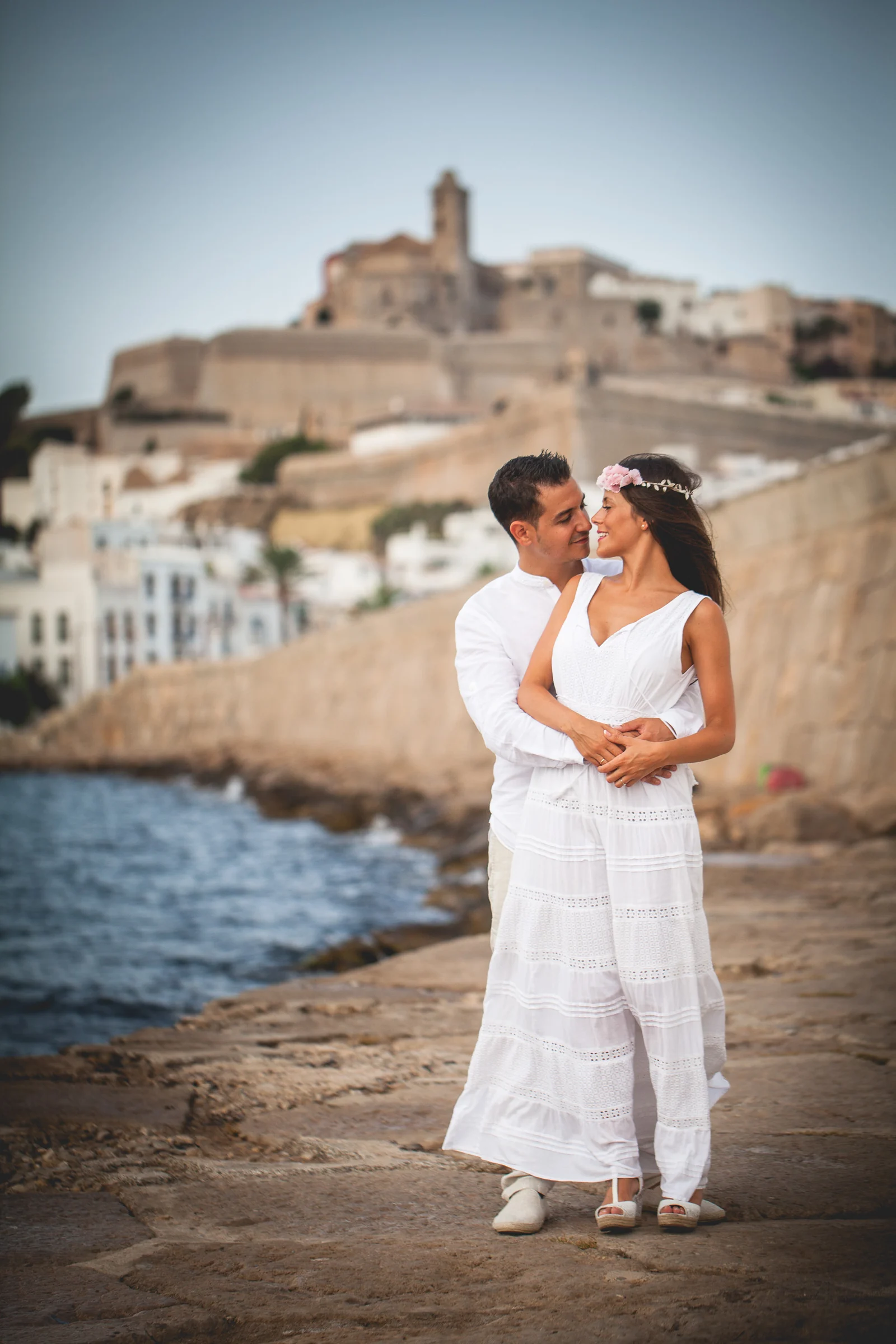 Alba y Jorge abrazados junto al mar con Ibiza al fondo, postboda de Alba y Jorge en Ibiza fotografiada por Pedro Zamorano.