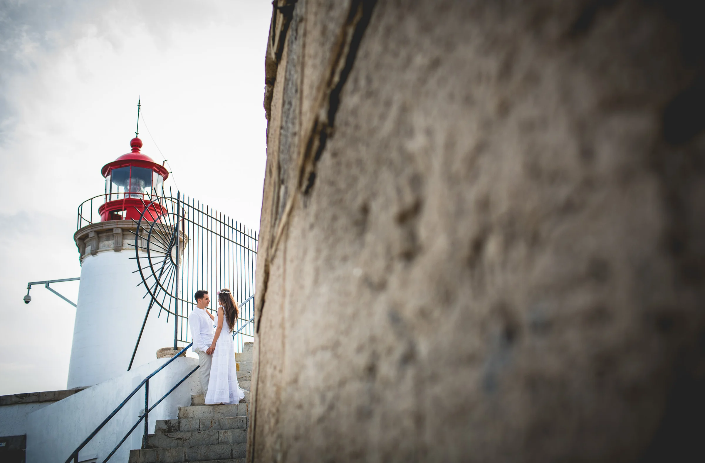 Alba junto al faro enmarcada por un muro, postboda de Alba y Jorge en Ibiza fotografiada por Pedro Zamorano.
