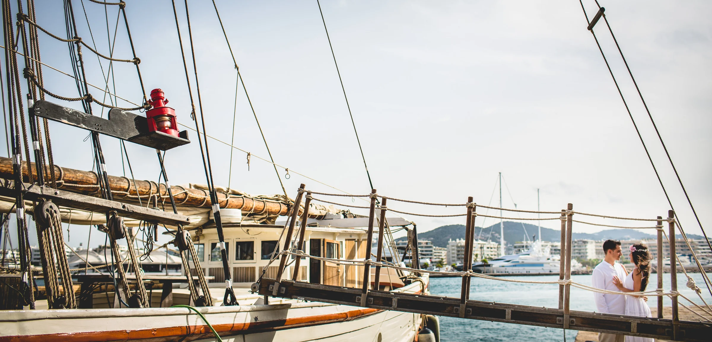 Pareja entre mástiles y embarcaciones del puerto, postboda de Alba y Jorge en Ibiza fotografiada por Pedro Zamorano.