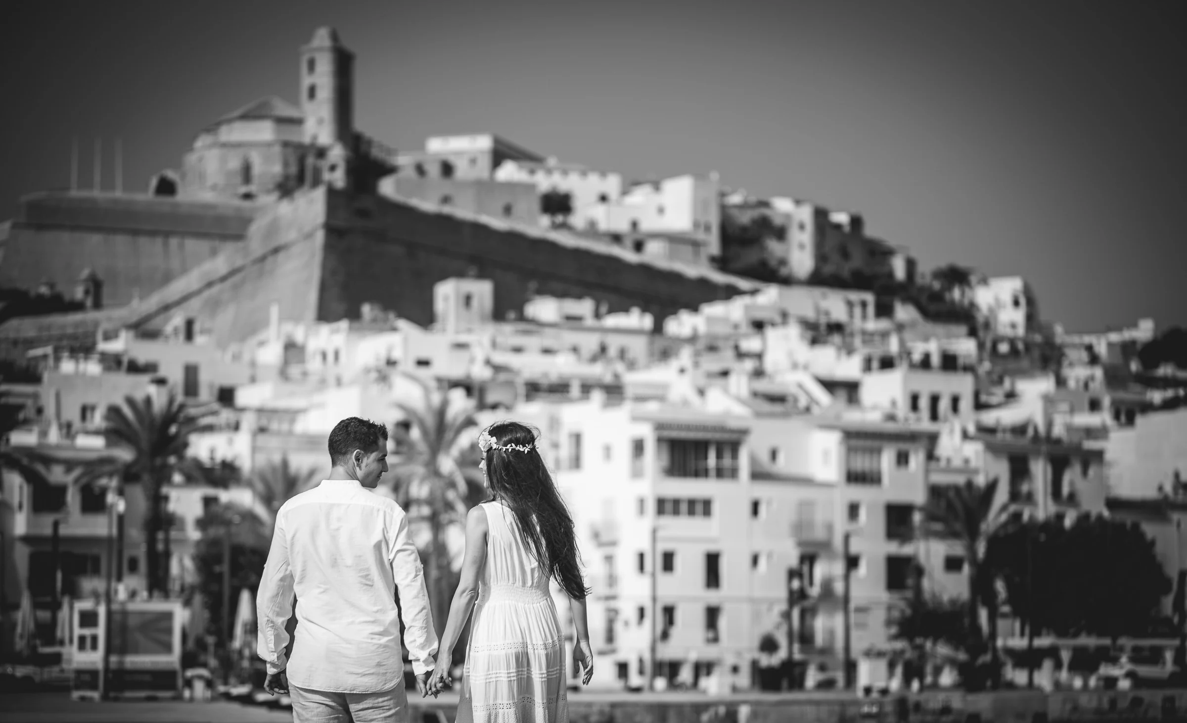 Alba y Jorge caminando frente a Dalt Vila en blanco y negro, postboda de Alba y Jorge en Ibiza fotografiada por Pedro Zamorano.
