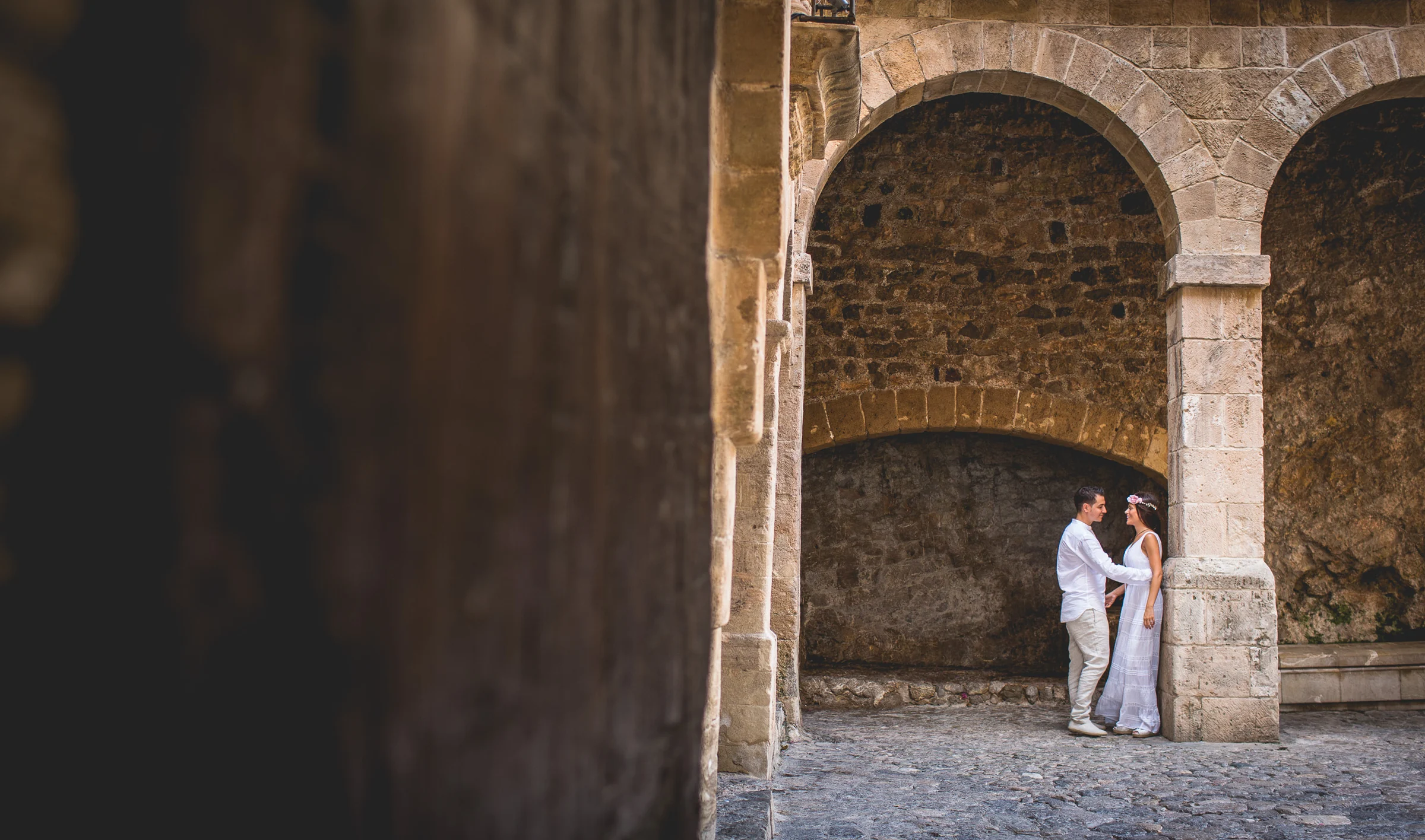 Pareja pequeña entre arcos históricos de Ibiza, postboda de Alba y Jorge en Ibiza fotografiada por Pedro Zamorano.