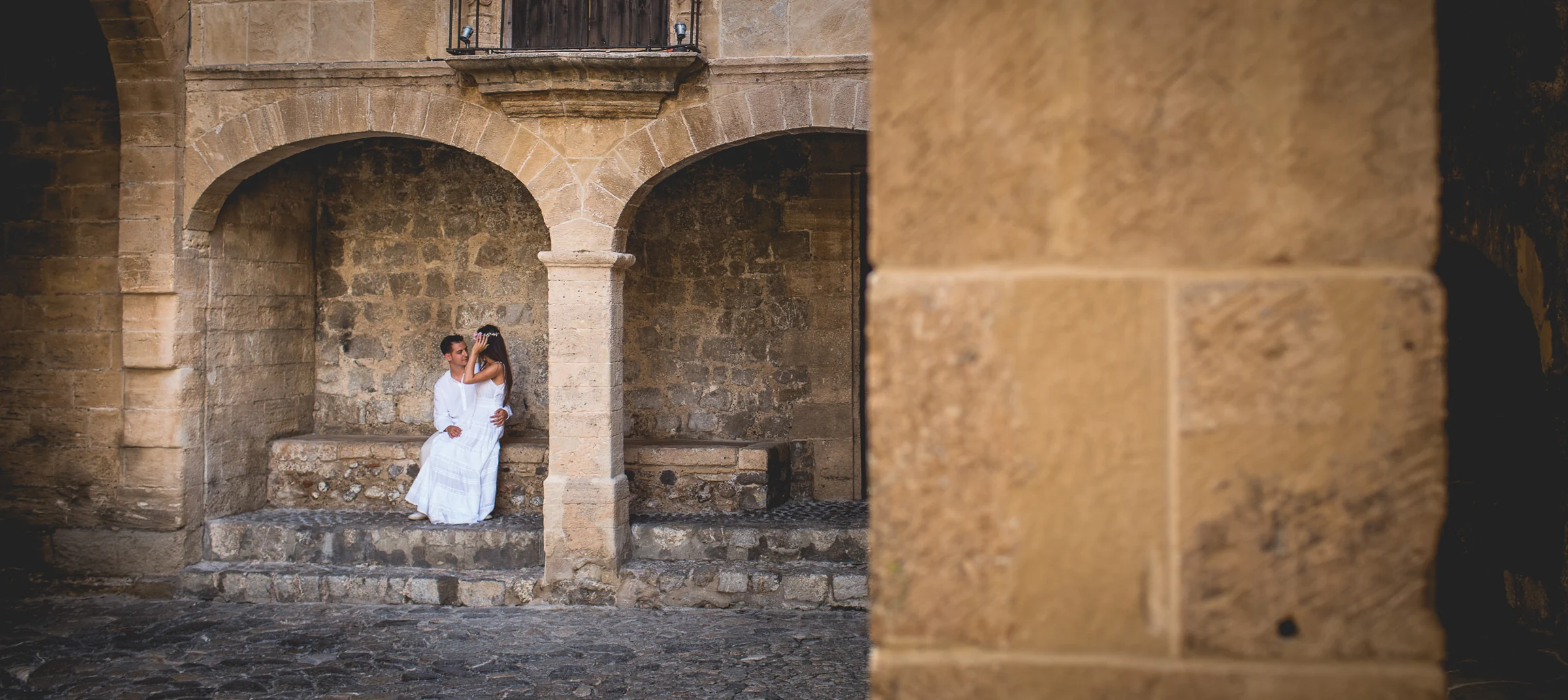 Alba y Jorge bajo los arcos con encuadre arquitectónico, postboda de Alba y Jorge en Ibiza fotografiada por Pedro Zamorano.