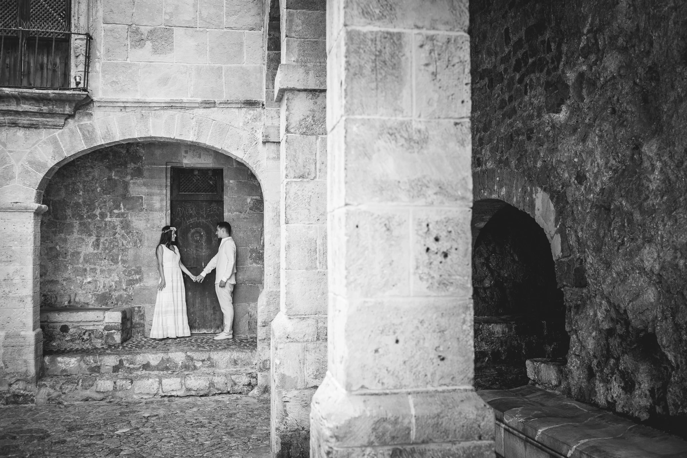 Pareja de la mano entre columnas en blanco y negro, postboda de Alba y Jorge en Ibiza fotografiada por Pedro Zamorano.