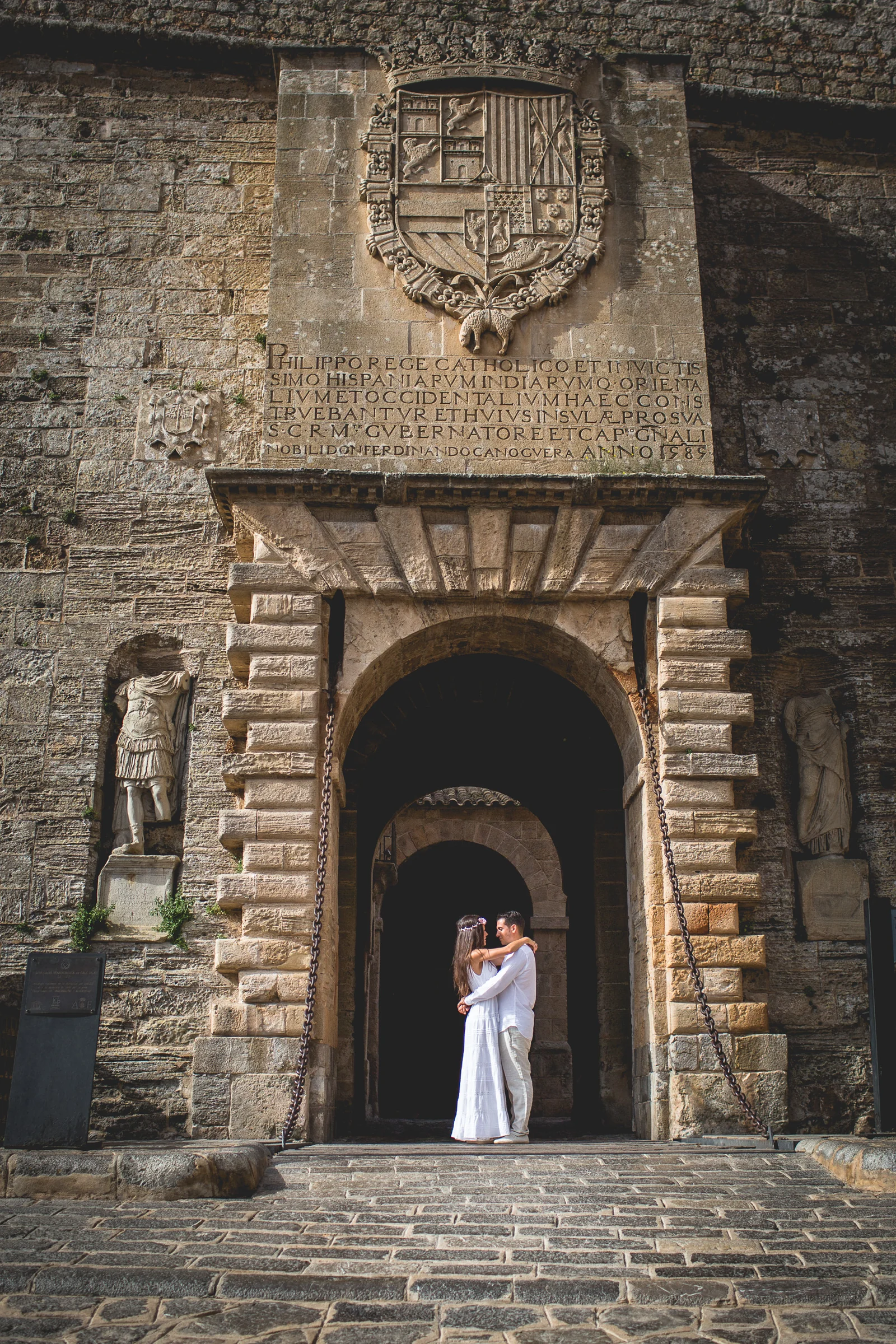 Alba y Jorge abrazados en la puerta monumental de Dalt Vila, postboda de Alba y Jorge en Ibiza fotografiada por Pedro Zamorano.