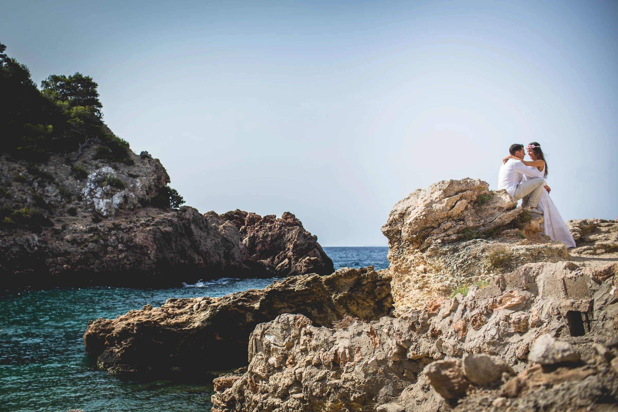 Alba y Jorge sentados sobre las rocas junto al mar, postboda de Alba y Jorge en Ibiza fotografiada por Pedro Zamorano.