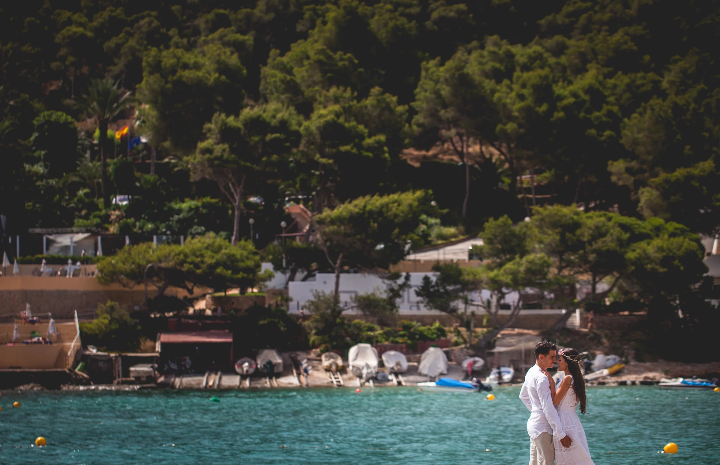 Alba y Jorge junto al agua con bosque costero al fondo, postboda de Alba y Jorge en Ibiza fotografiada por Pedro Zamorano.