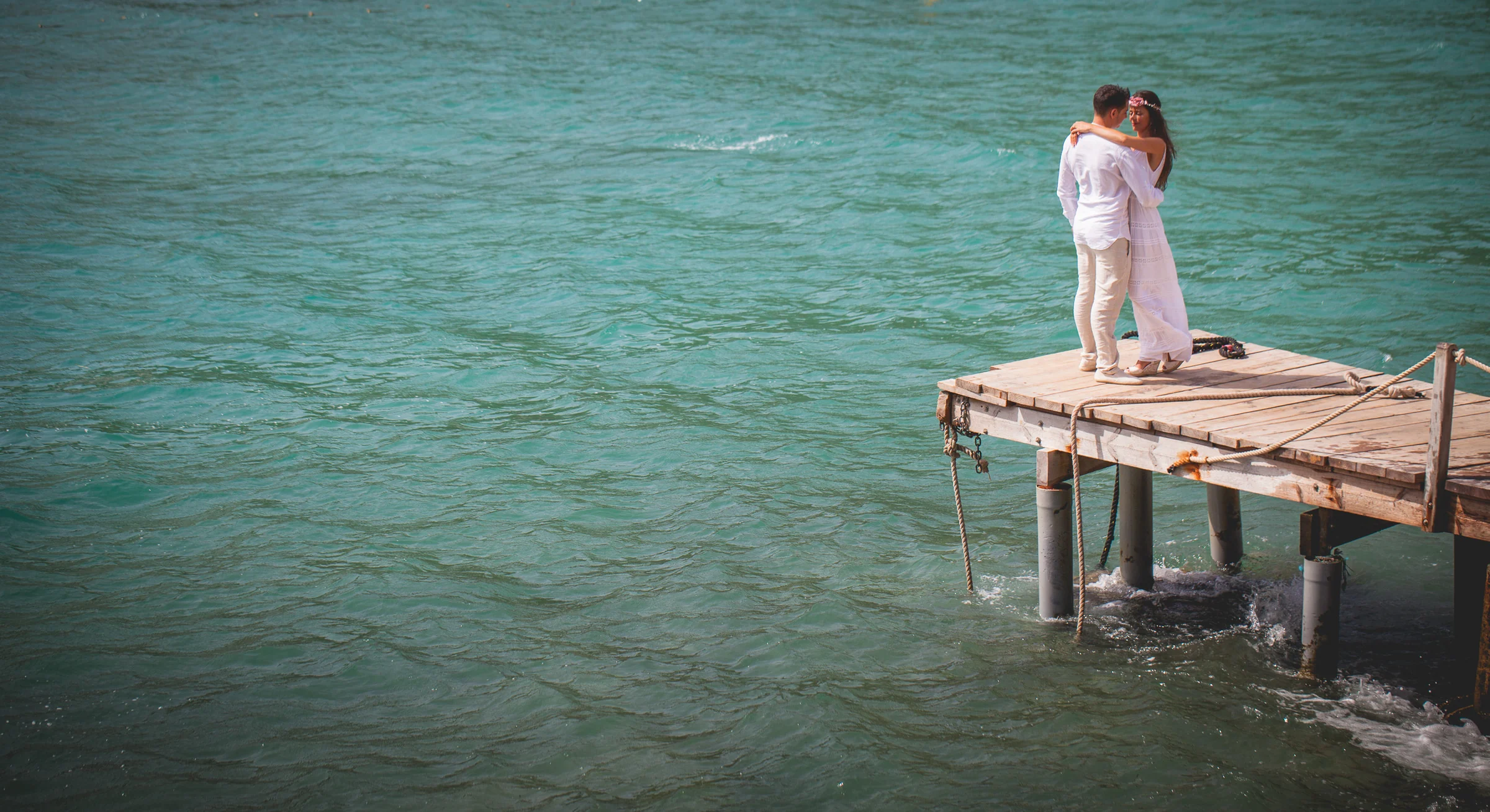 Pareja abrazada en el extremo de un pantalán sobre agua turquesa, postboda de Alba y Jorge en Ibiza fotografiada por Pedro Zamorano.