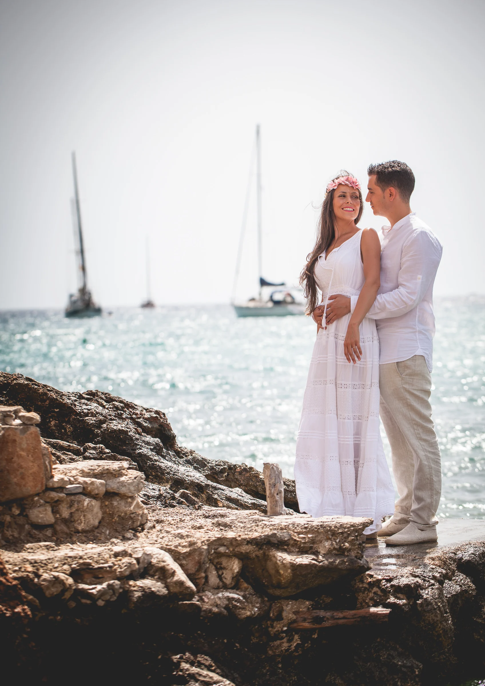 Retrato vertical de la pareja junto al mar y veleros, postboda de Alba y Jorge en Ibiza fotografiada por Pedro Zamorano.