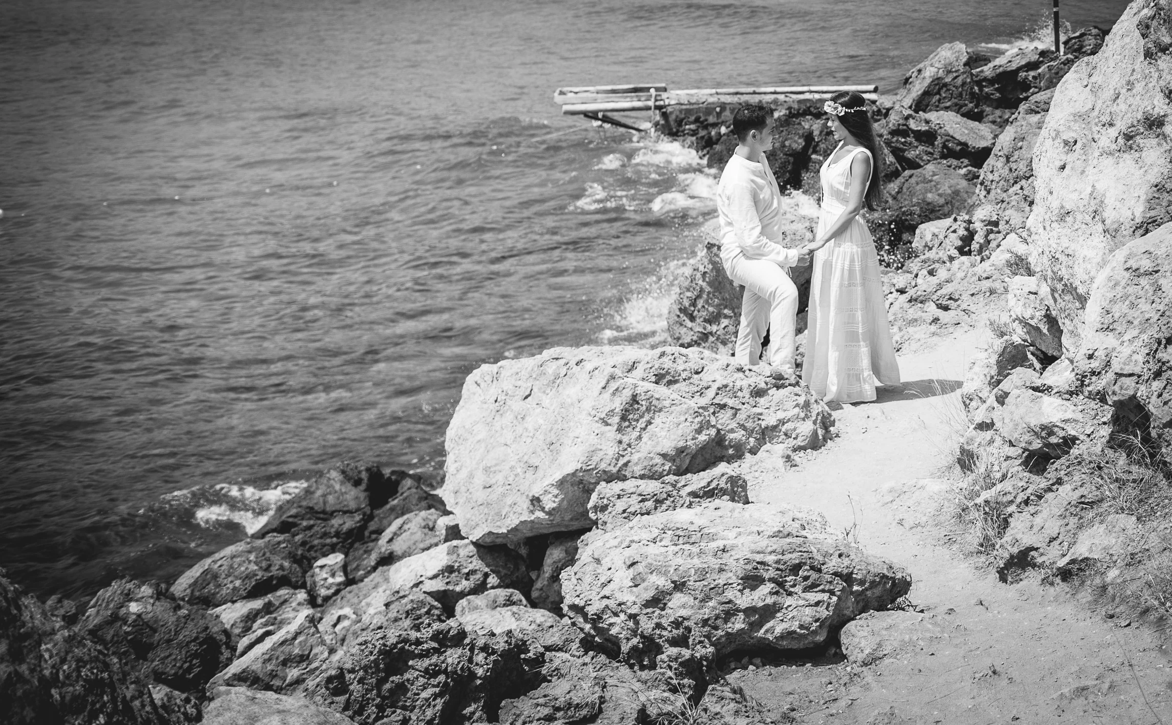 Alba y Jorge entre rocas costeras en blanco y negro, postboda de Alba y Jorge en Ibiza fotografiada por Pedro Zamorano.