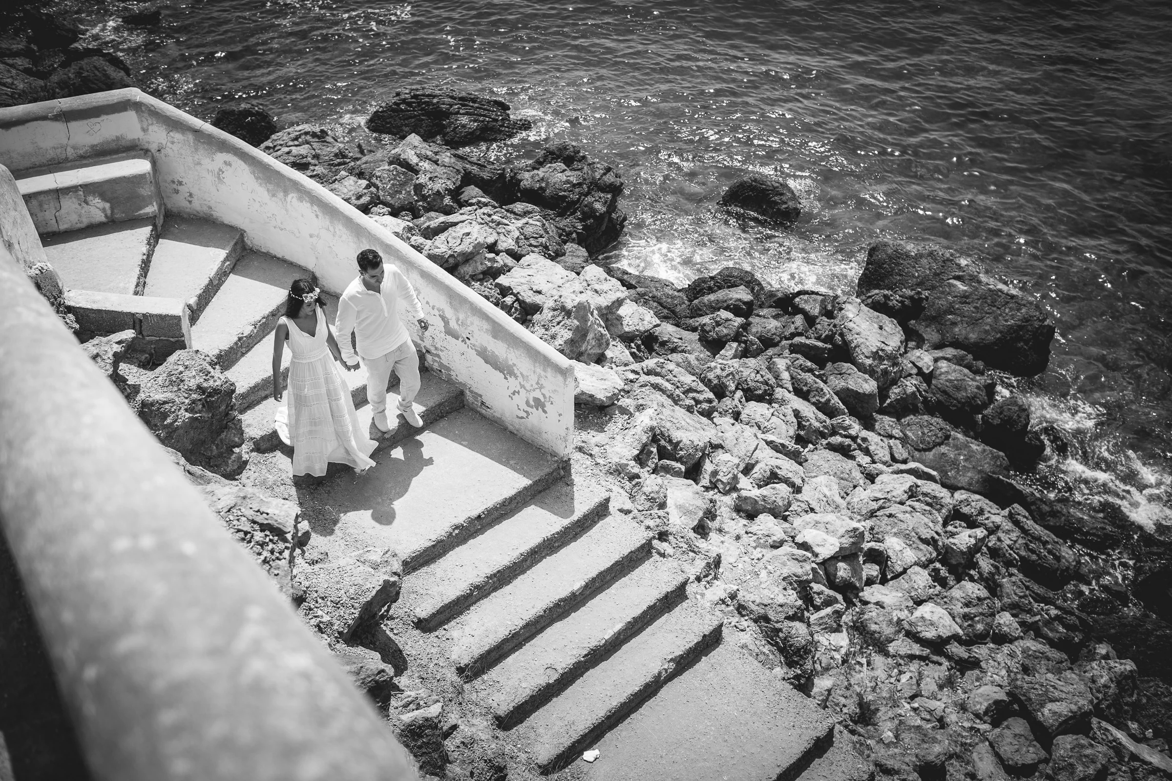 Pareja caminando por escaleras junto al mar en blanco y negro, postboda de Alba y Jorge en Ibiza fotografiada por Pedro Zamorano.