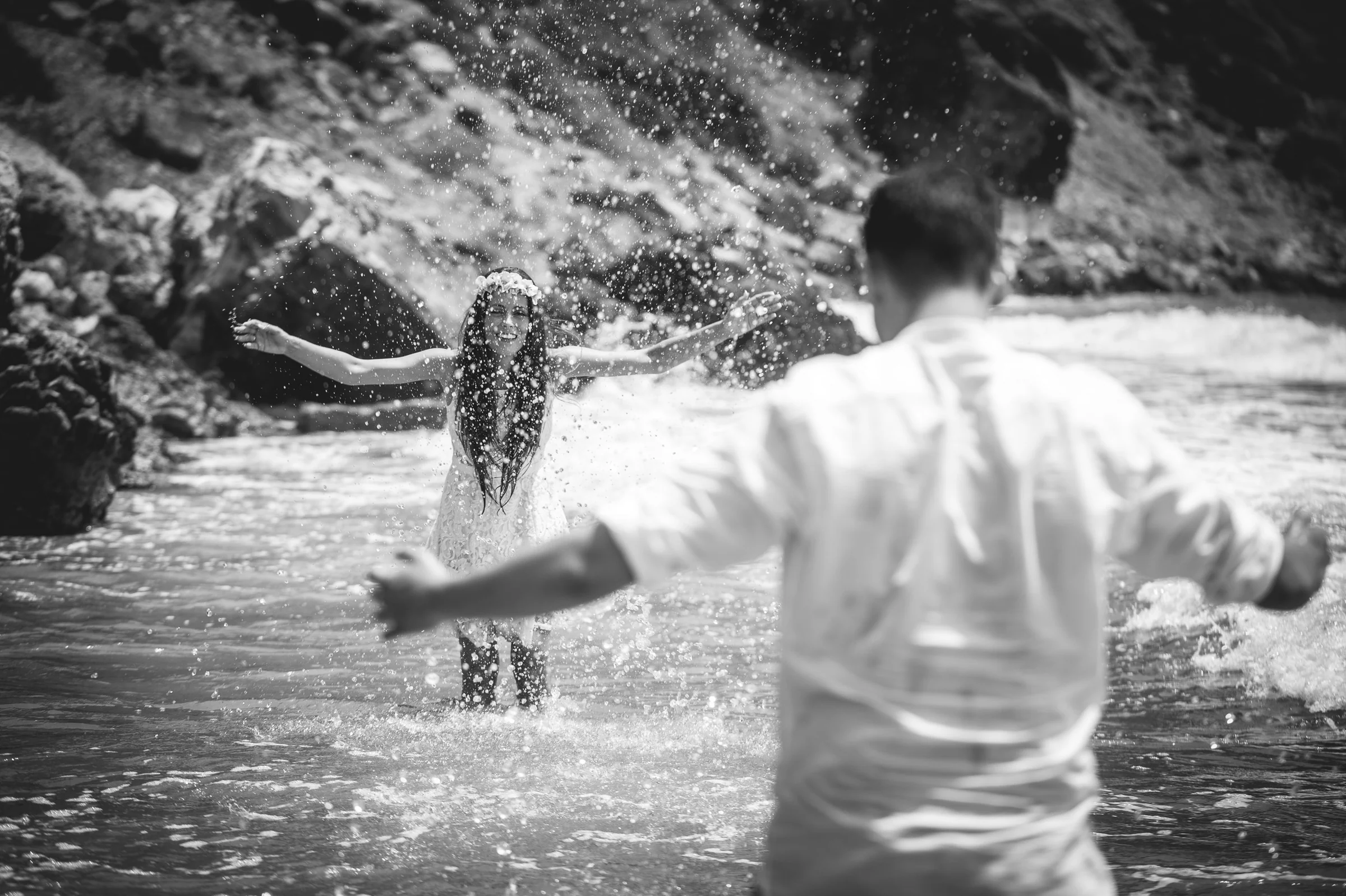 Alba corriendo hacia Jorge entre salpicaduras en blanco y negro, postboda de Alba y Jorge en Ibiza fotografiada por Pedro Zamorano.