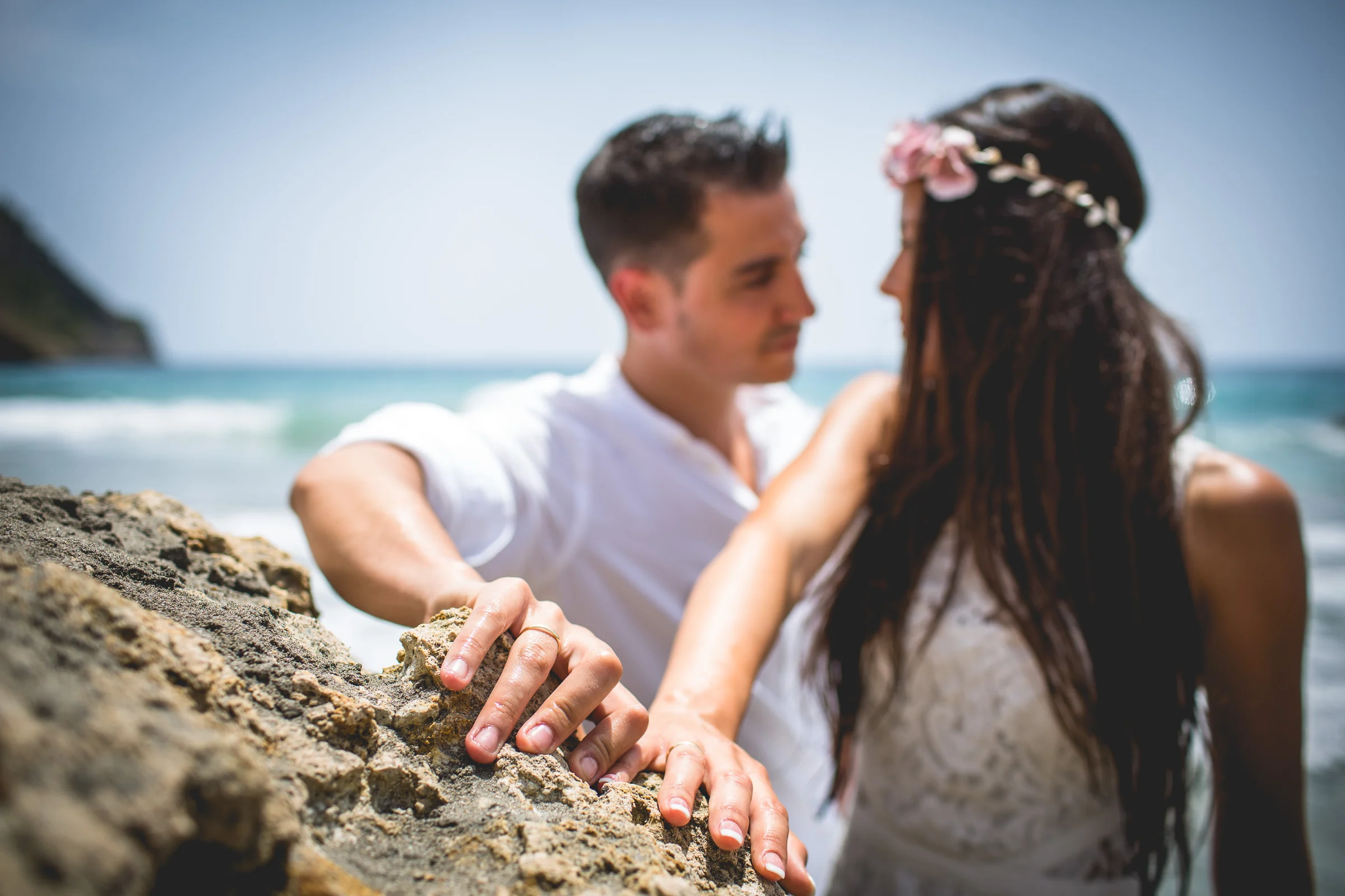 Primer plano de las manos de la pareja sobre una roca, postboda de Alba y Jorge en Ibiza fotografiada por Pedro Zamorano.
