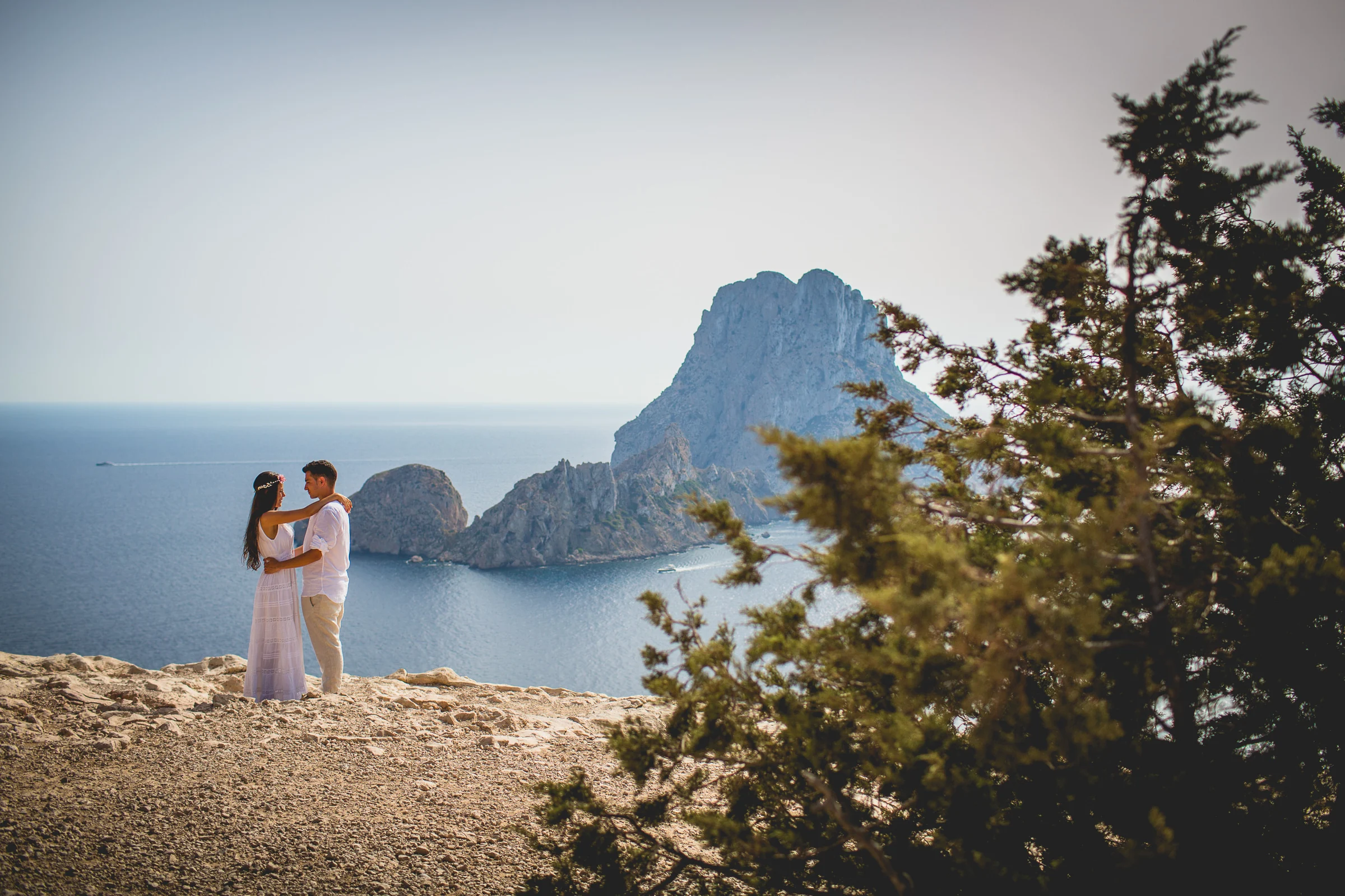Pareja junto a Es Vedrà con árbol en primer plano, postboda de Alba y Jorge en Ibiza fotografiada por Pedro Zamorano.