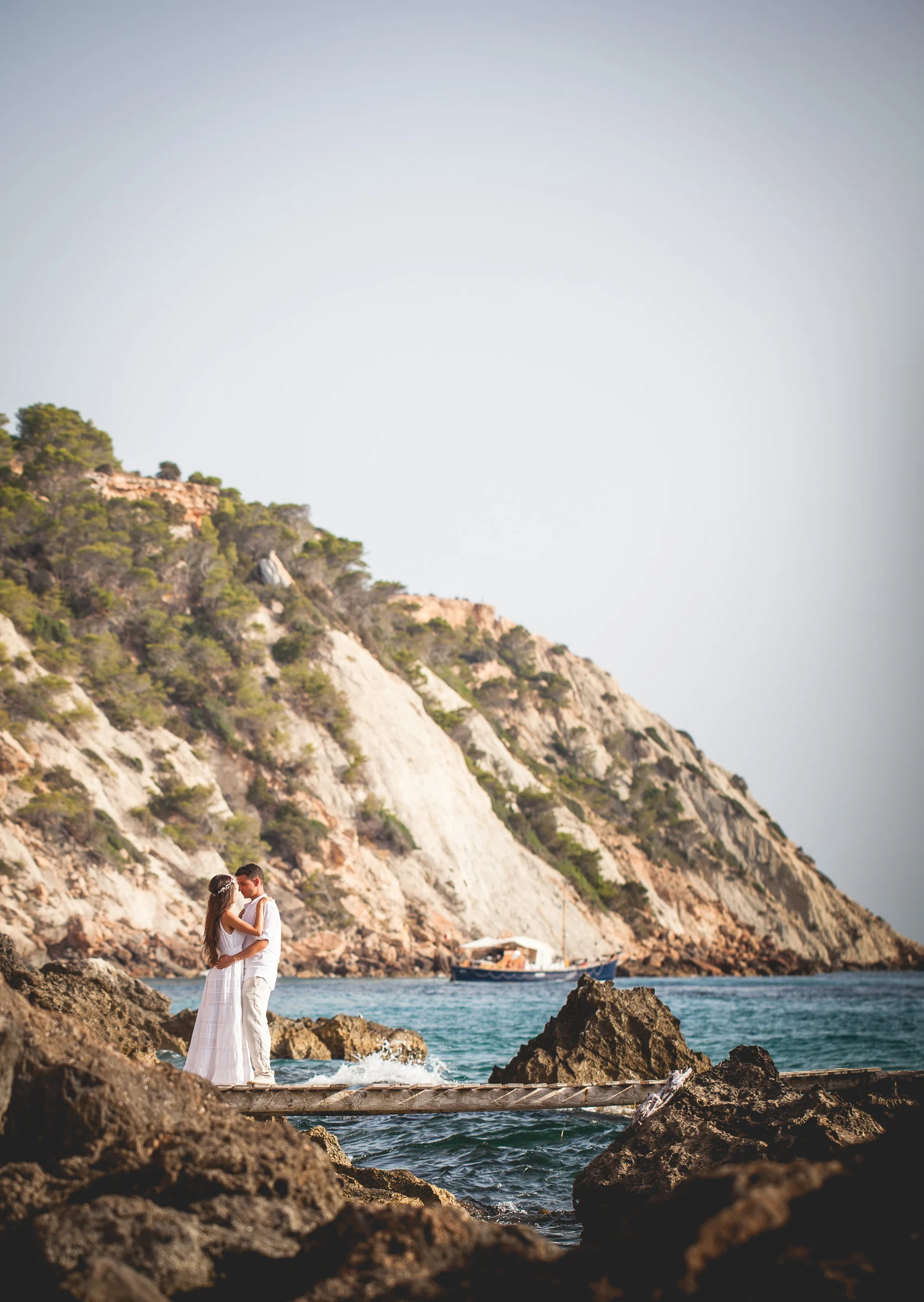 Alba y Jorge entre rocas con gran espacio de cielo, postboda de Alba y Jorge en Ibiza fotografiada por Pedro Zamorano.