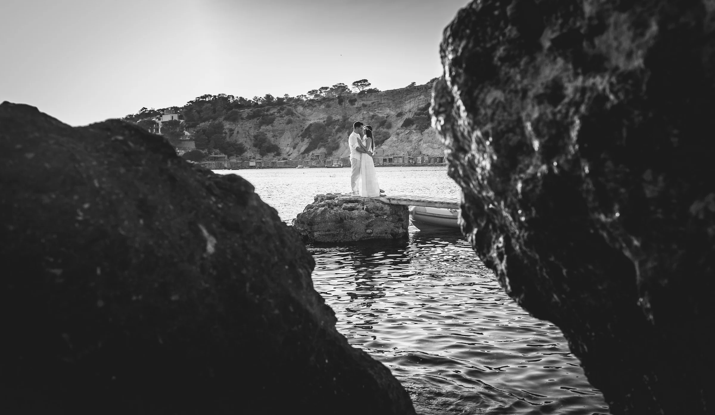 Alba y Jorge enmarcados entre dos rocas en blanco y negro, postboda de Alba y Jorge en Ibiza fotografiada por Pedro Zamorano.