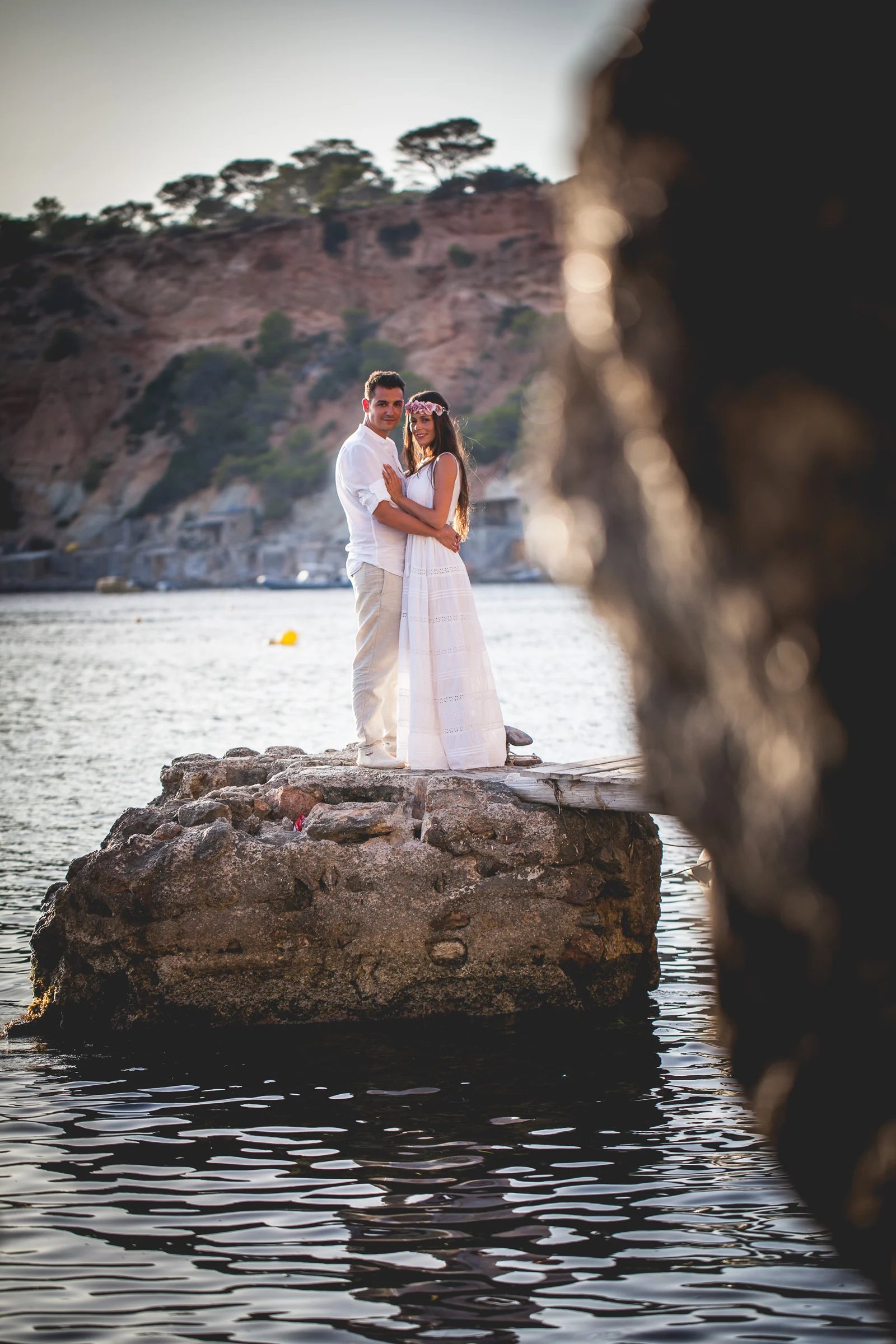 Retrato vertical de Alba y Jorge sobre una roca al atardecer, postboda de Alba y Jorge en Ibiza fotografiada por Pedro Zamorano.