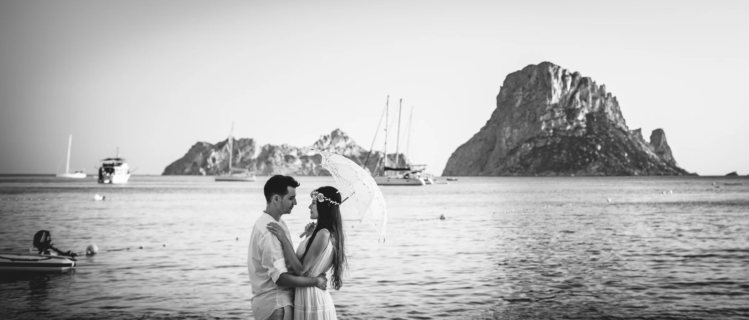 Retrato en blanco y negro con sombrilla y Es Vedrà, postboda de Alba y Jorge en Ibiza fotografiada por Pedro Zamorano.