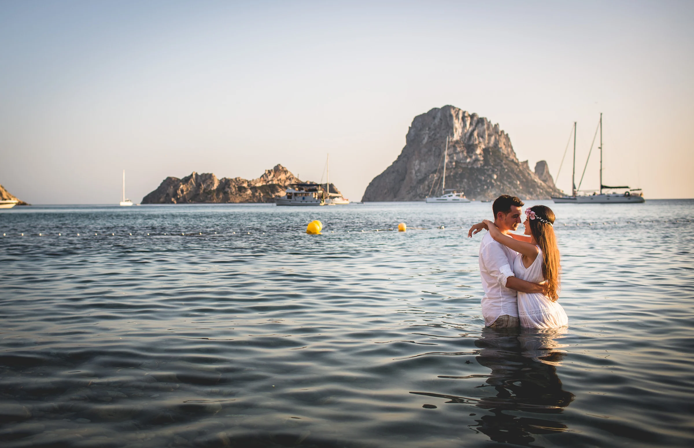 Pareja abrazada dentro del mar con Es Vedrà al fondo, postboda de Alba y Jorge en Ibiza fotografiada por Pedro Zamorano.