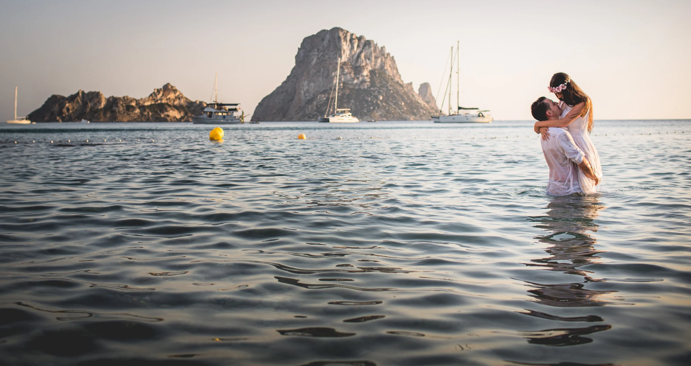 Alba y Jorge abrazados dentro del mar con Es Vedrà, postboda de Alba y Jorge en Ibiza fotografiada por Pedro Zamorano.