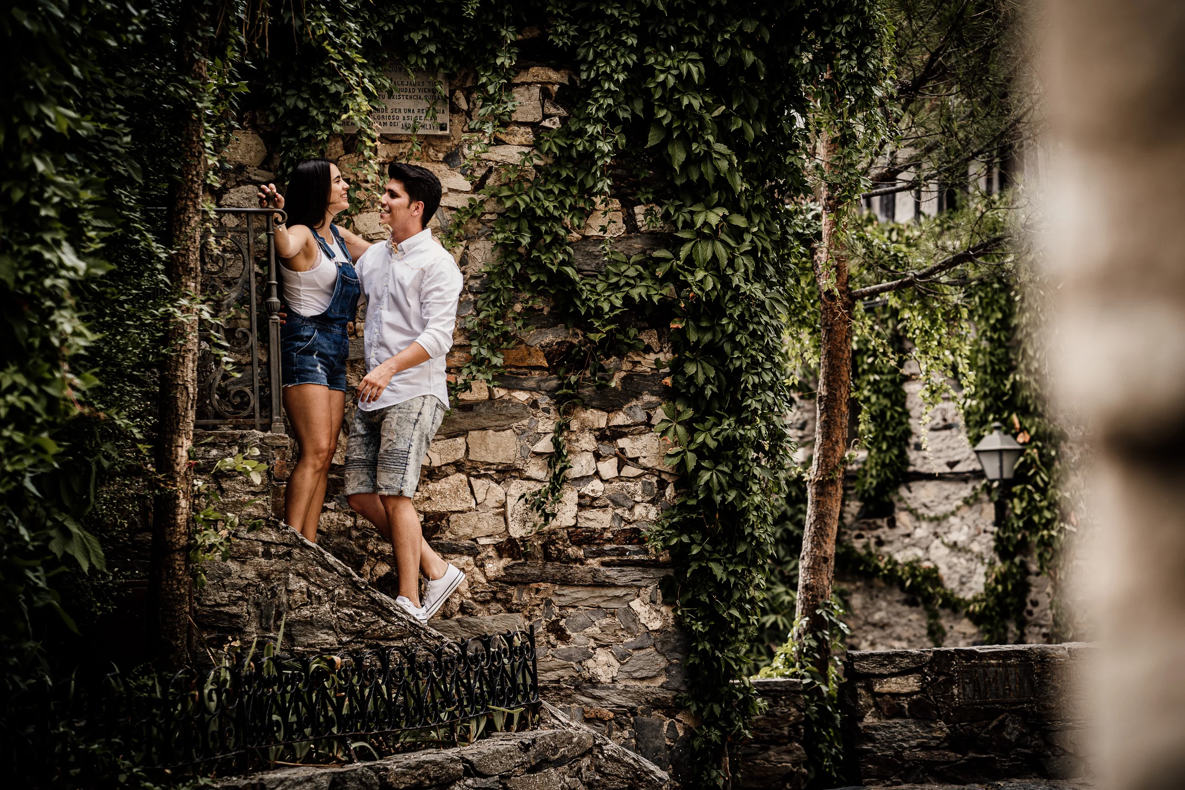 Aritz y Laura posan en una escalera de piedra rodeados de fachadas tradicionales y vegetación en Patones.