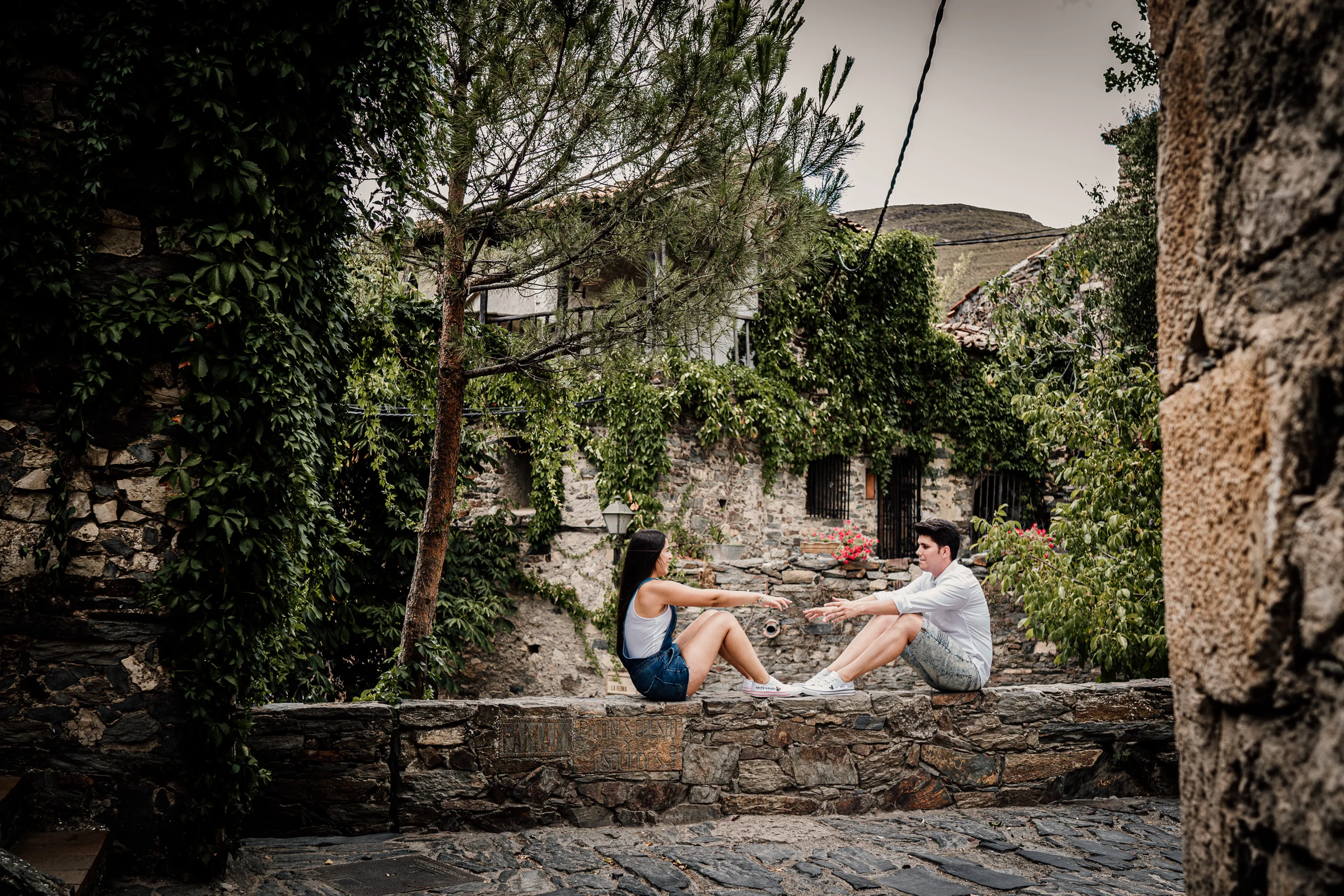 Aritz y Laura se sientan frente a frente sobre un muro de piedra durante su sesión de preboda en Patones.