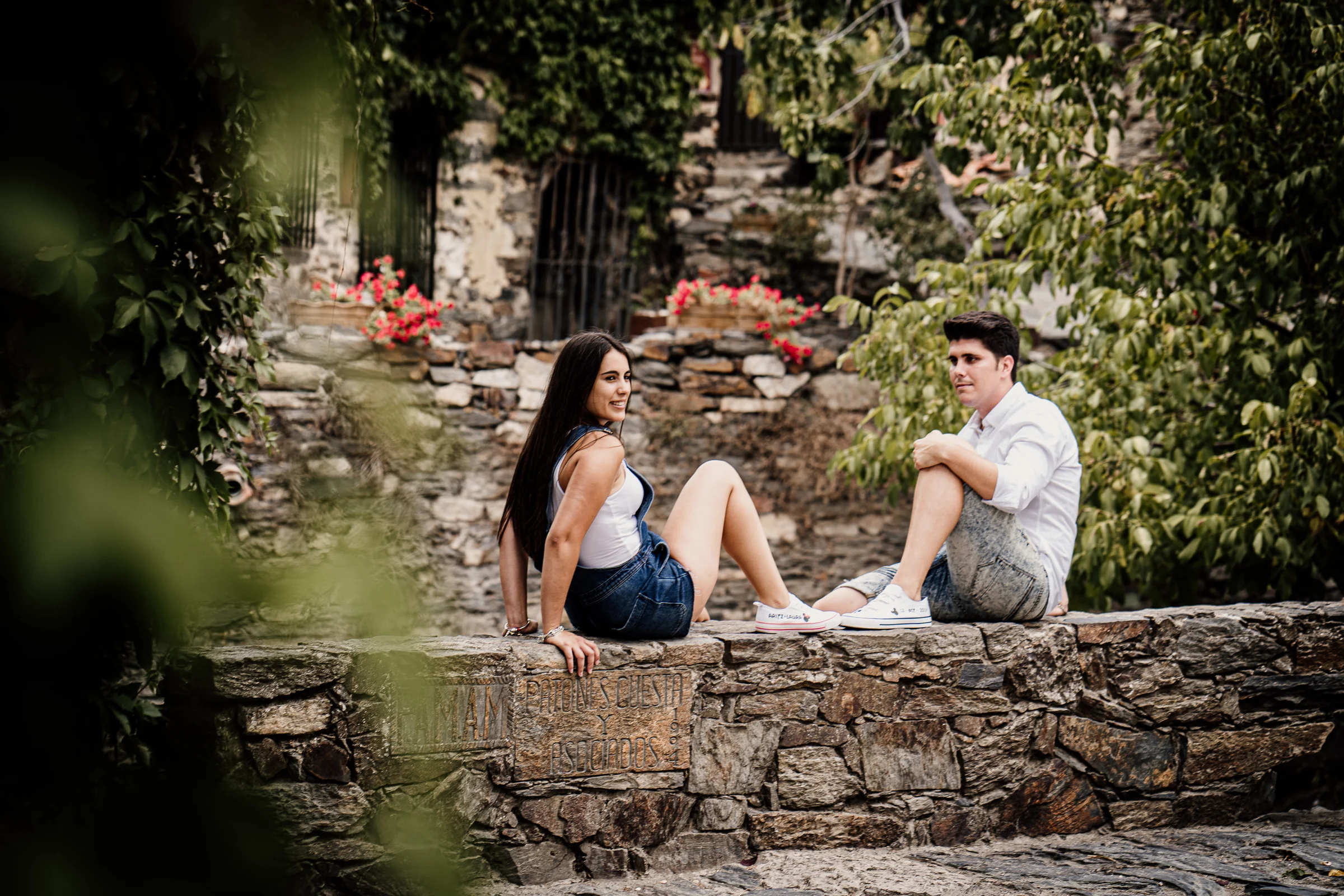 Laura y Aritz comparten un momento tranquilo sentados entre muros de pizarra y plantas en Patones.