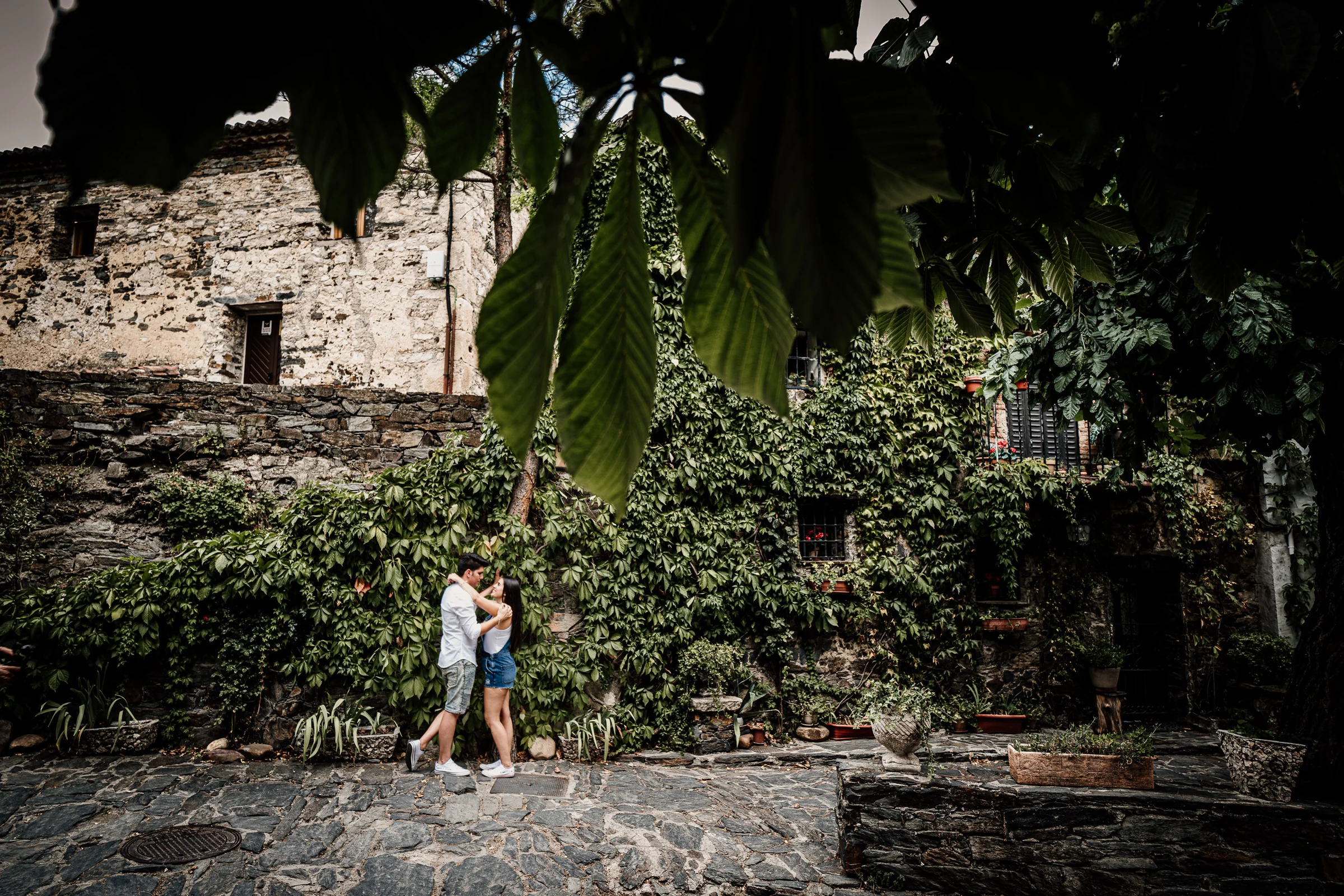 Aritz y Laura se abrazan en una calle empedrada rodeada de fachadas de piedra y hiedra en Patones.