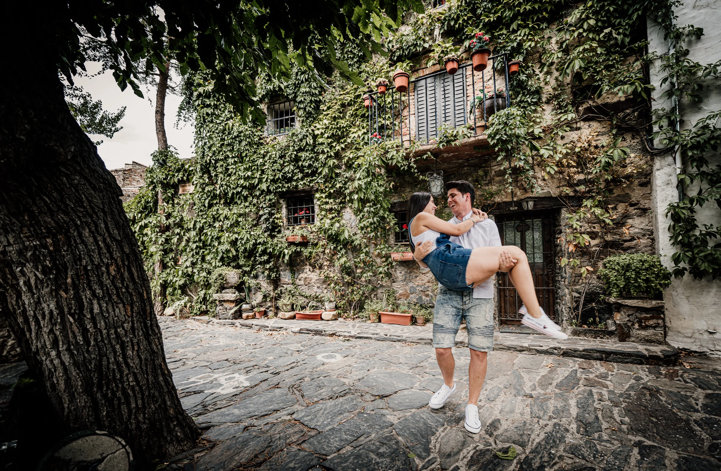 Aritz levanta a Laura entre risas en una calle de piedra durante su preboda en Patones.