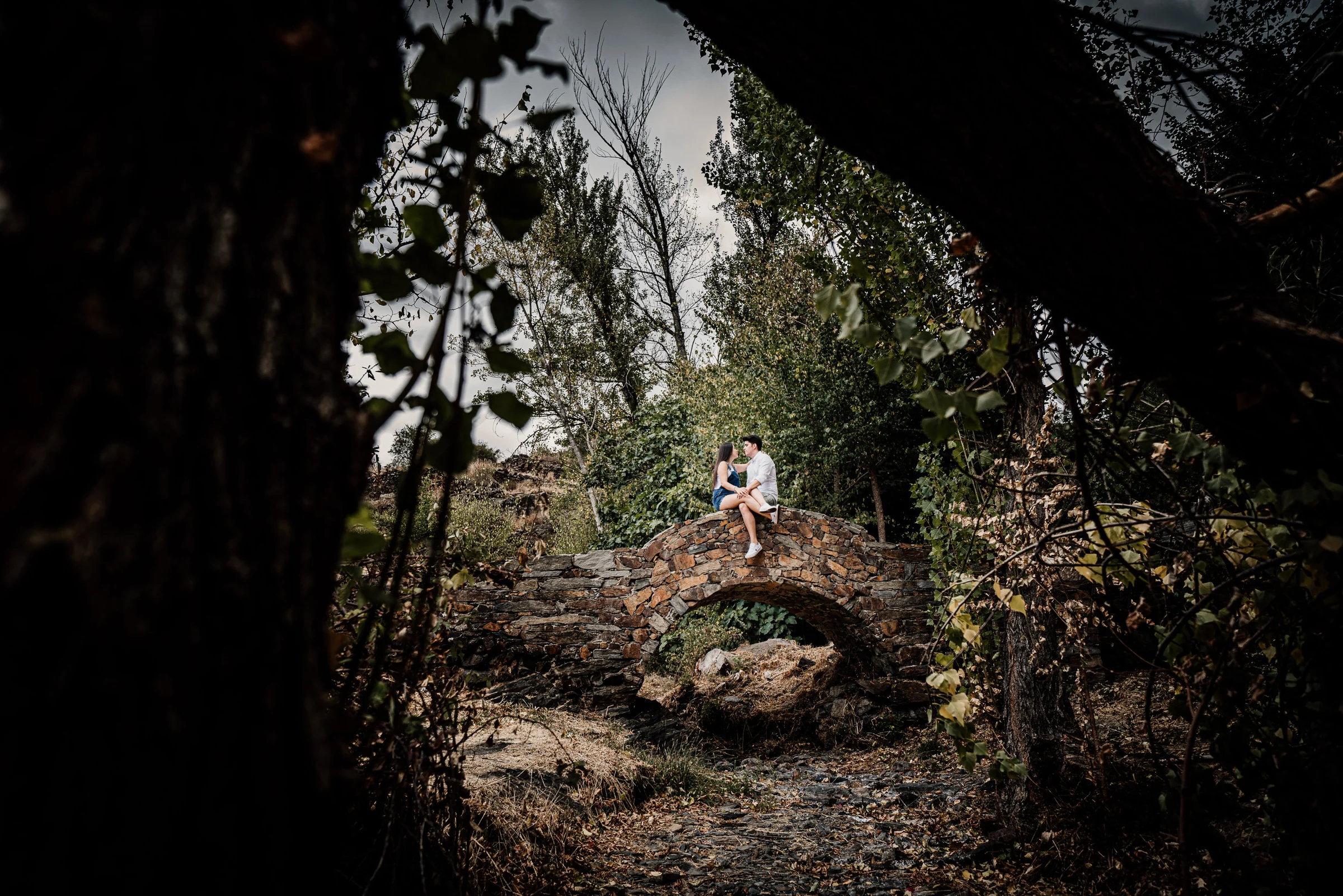 Aritz y Laura aparecen a lo lejos enmarcados por piedra y vegetación durante su preboda en Patones.