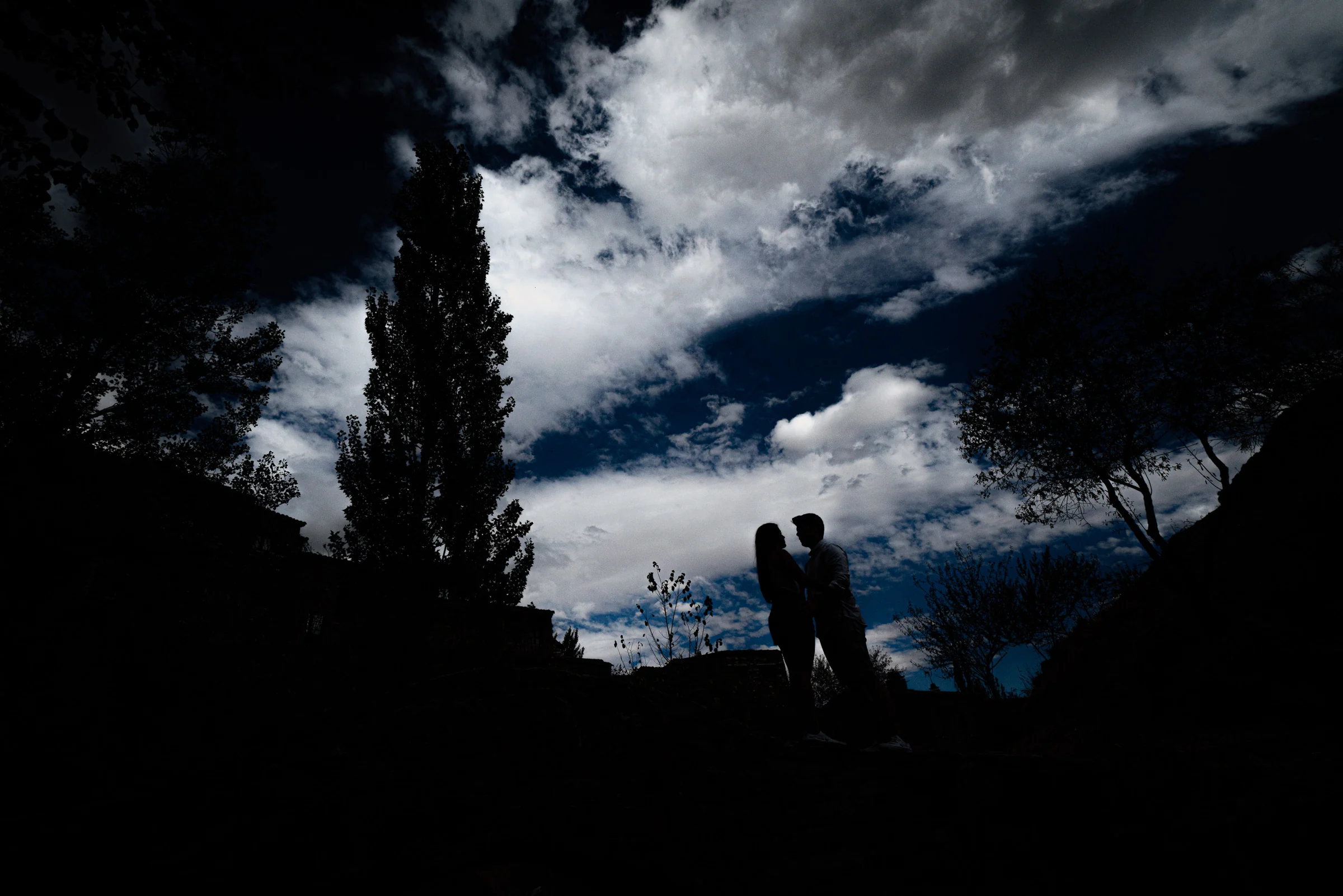 Silueta de Aritz y Laura bajo un cielo de nubes dramáticas durante su preboda en Patones.