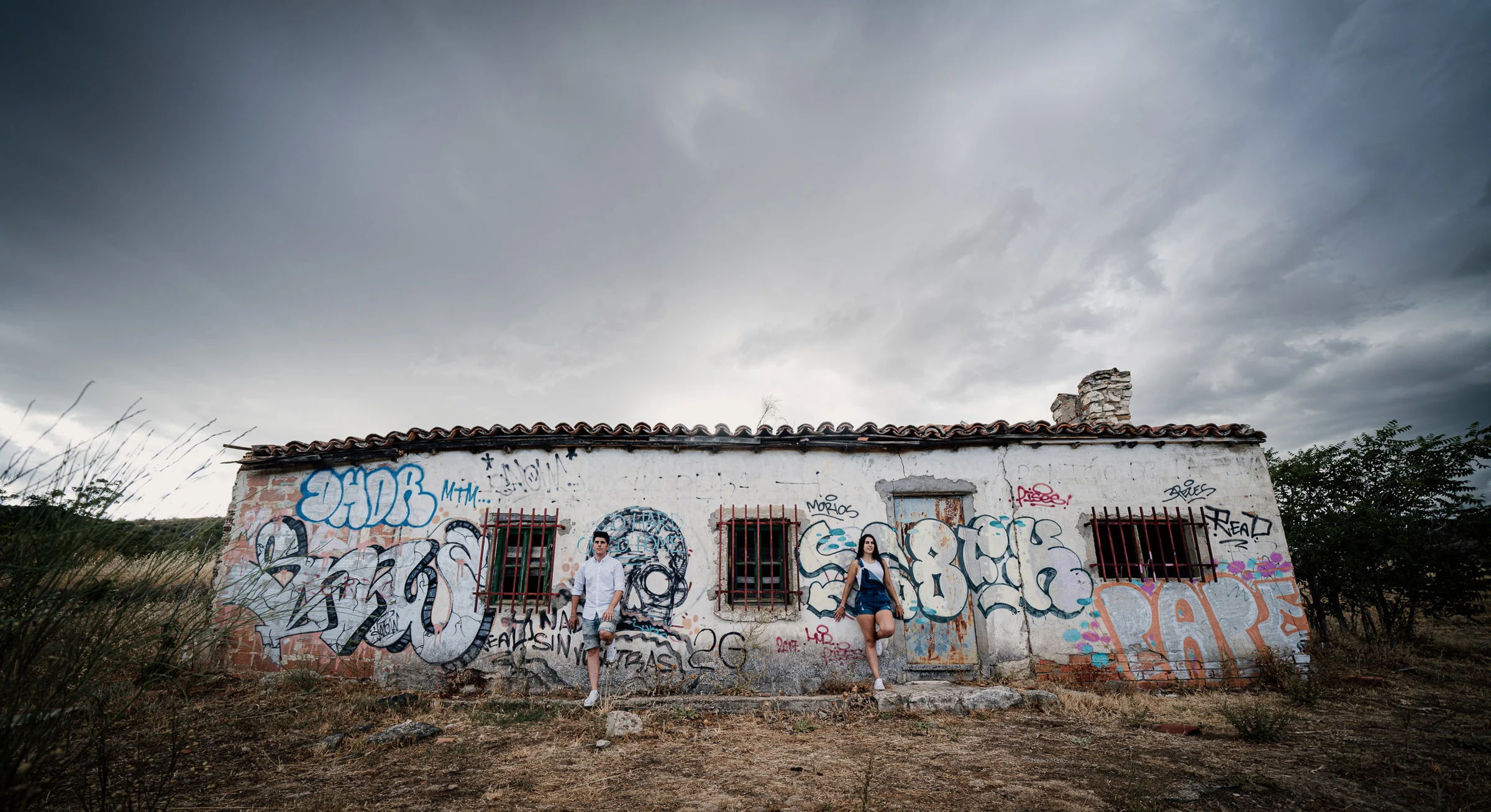 Aritz y Laura posan separados frente a una construcción abandonada con grafitis en el entorno de Patones.