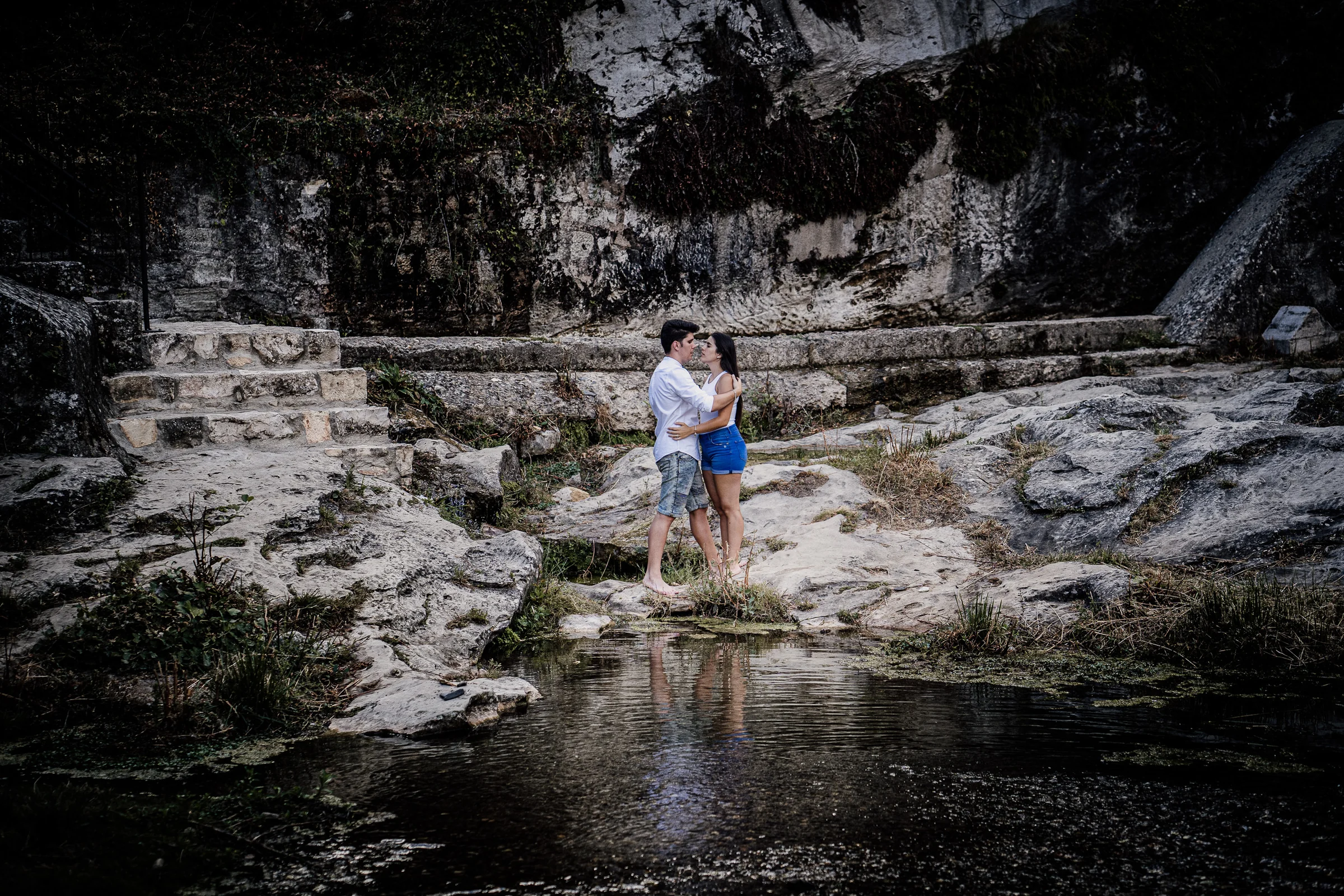 Aritz y Laura se abrazan descalzos junto al agua y las rocas durante su preboda en Patones.