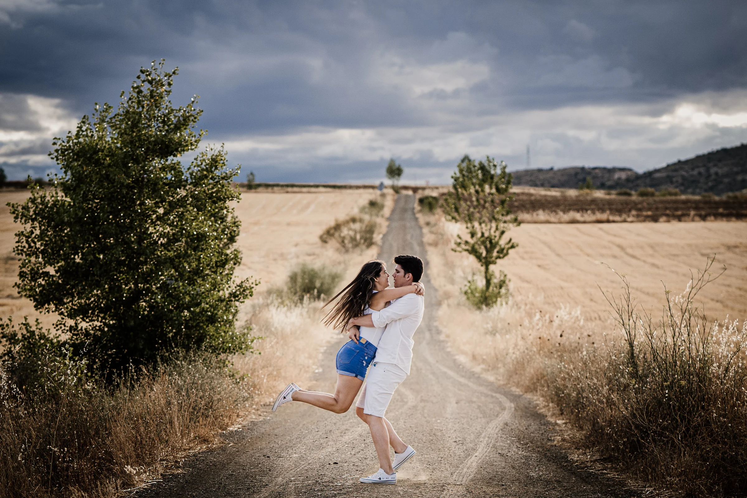 Aritz levanta a Laura en mitad de un camino entre campos durante su preboda en los alrededores de Patones.