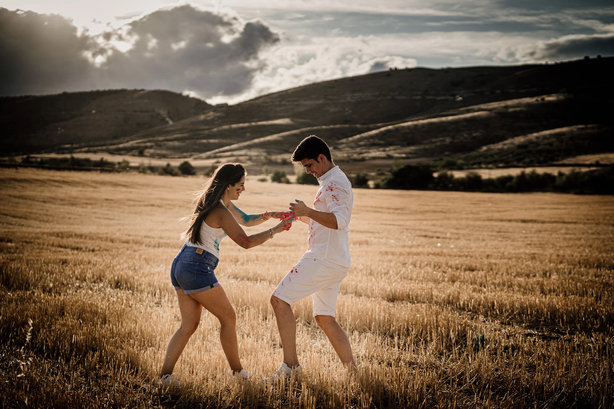 Aritz y Laura juegan con pintura de colores en un campo al atardecer durante su preboda en Patones.