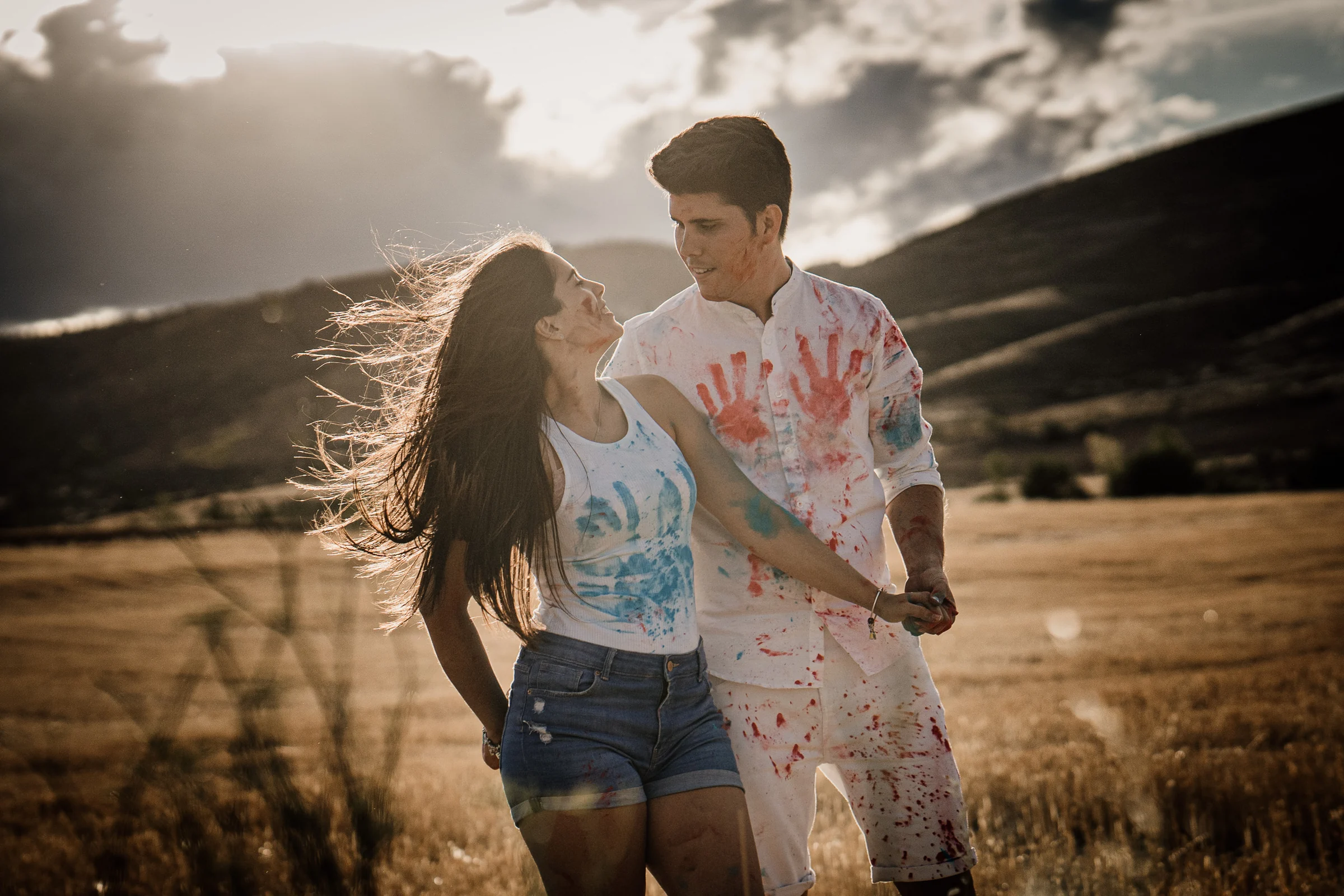 Aritz y Laura caminan cogidos de la mano cubiertos de pintura y a contraluz en los campos de Patones.