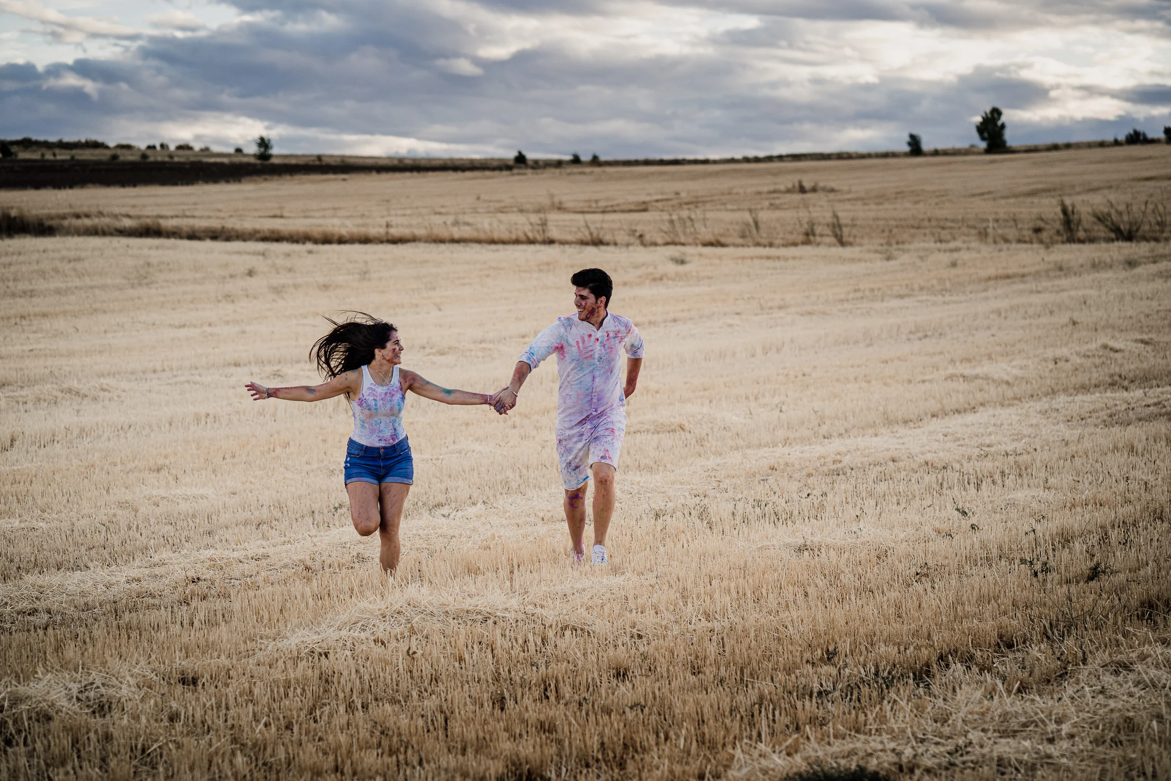 Aritz y Laura corren de la mano entre los rastrojos durante su preboda en los campos de Patones.