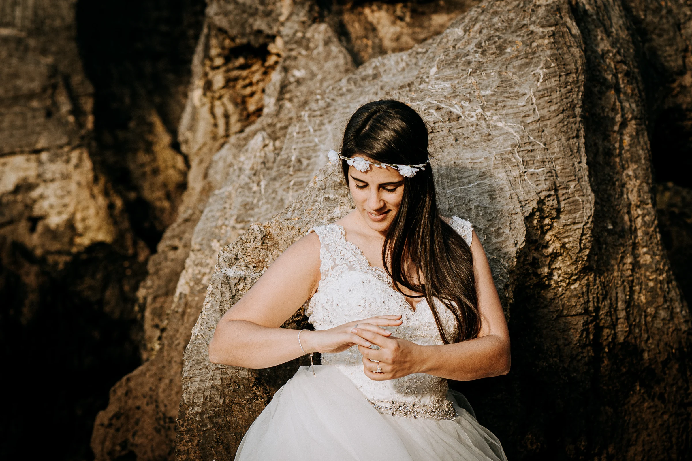 Detalle del vestido y la novia junto a las rocas durante una sesión de postboda en El Molino, cerca de Llanes, Asturias.