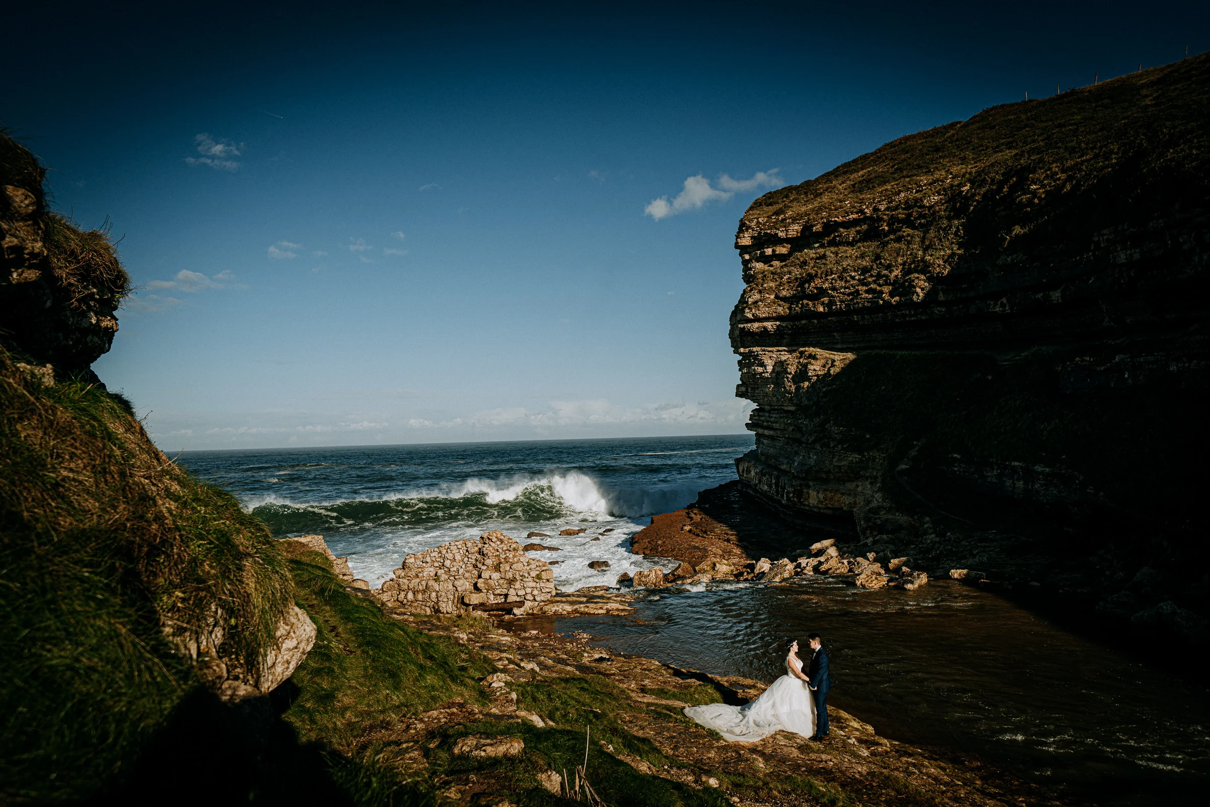 Novia en un paisaje de acantilados y oleaje durante una sesión de postboda en El Molino, cerca de Llanes, Asturias.