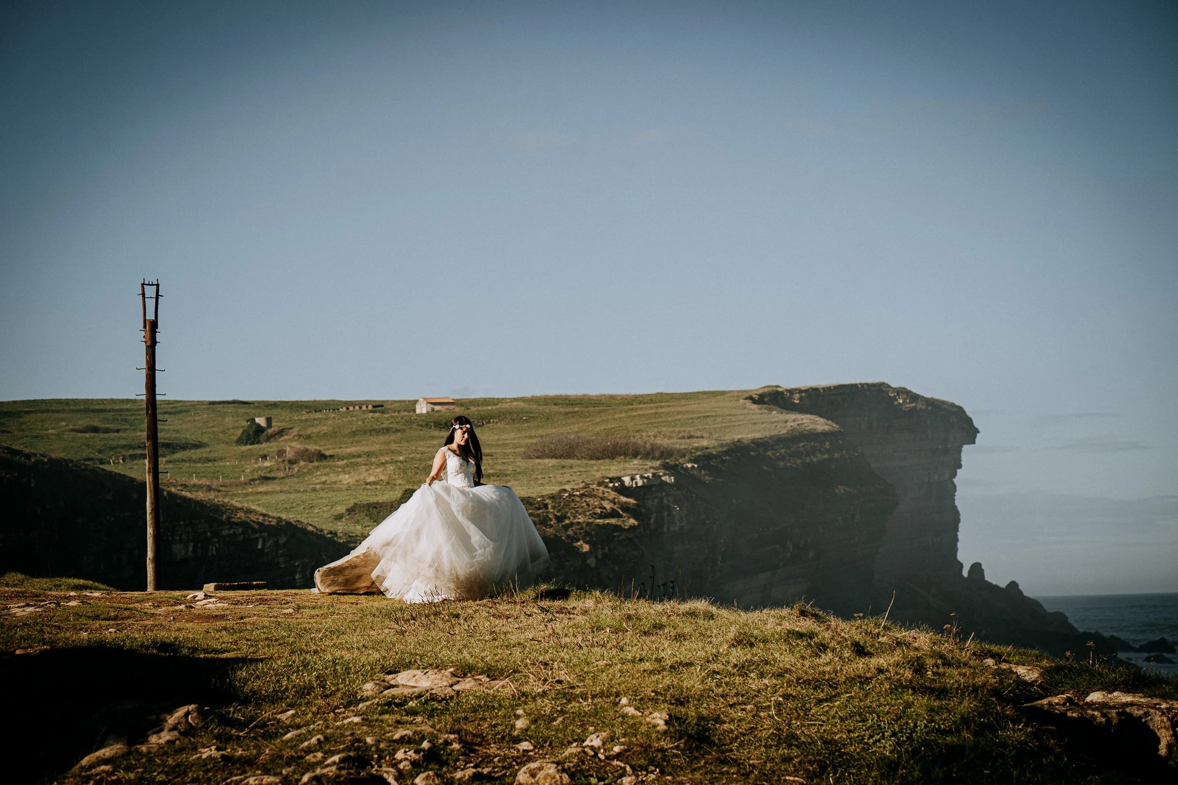 Novia frente a los acantilados y el mar durante una sesión de postboda en El Molino, cerca de Llanes, Asturias.