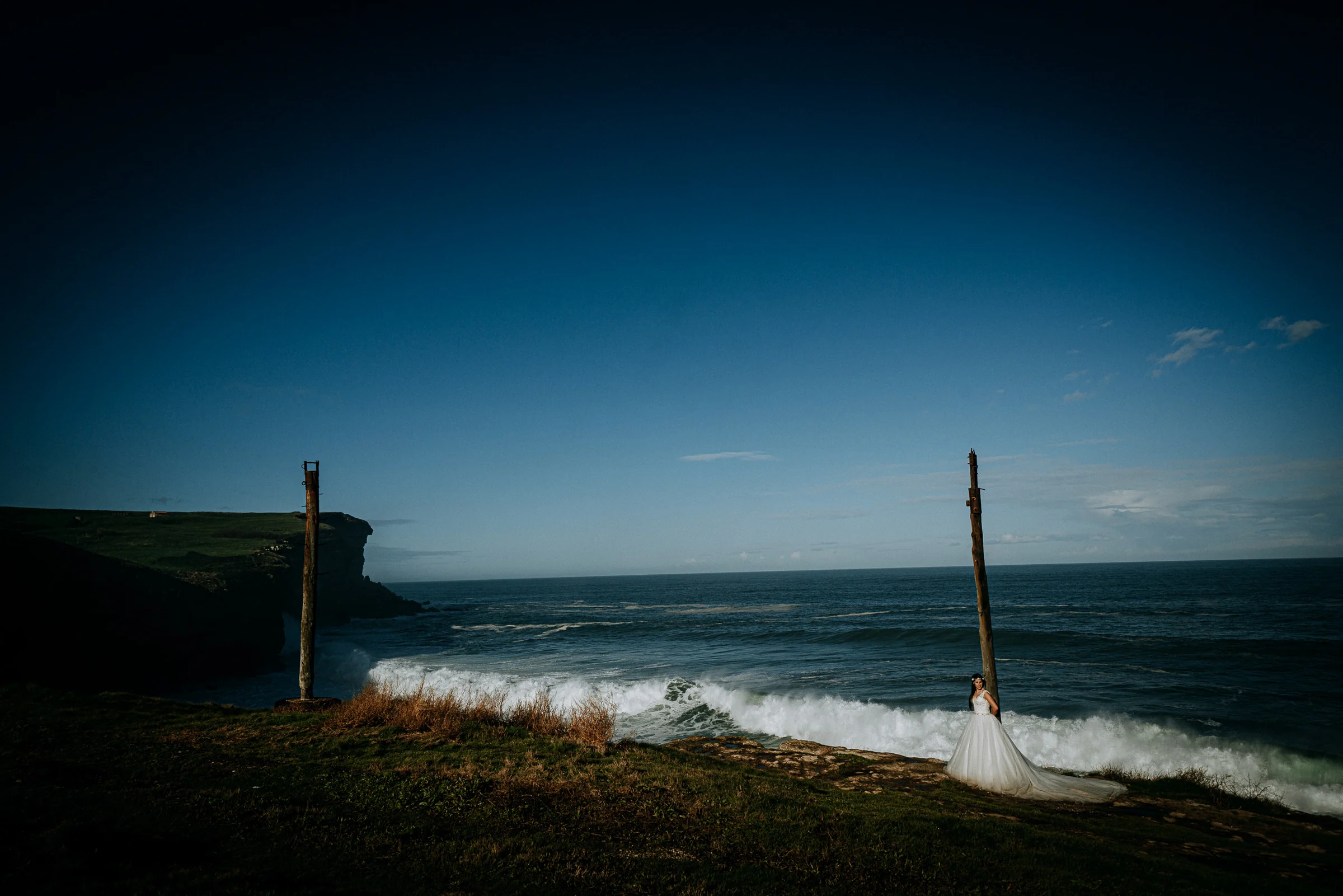 Novia frente al mar en un paisaje costero minimalista durante una sesión de postboda en El Molino, cerca de Llanes, Asturias.