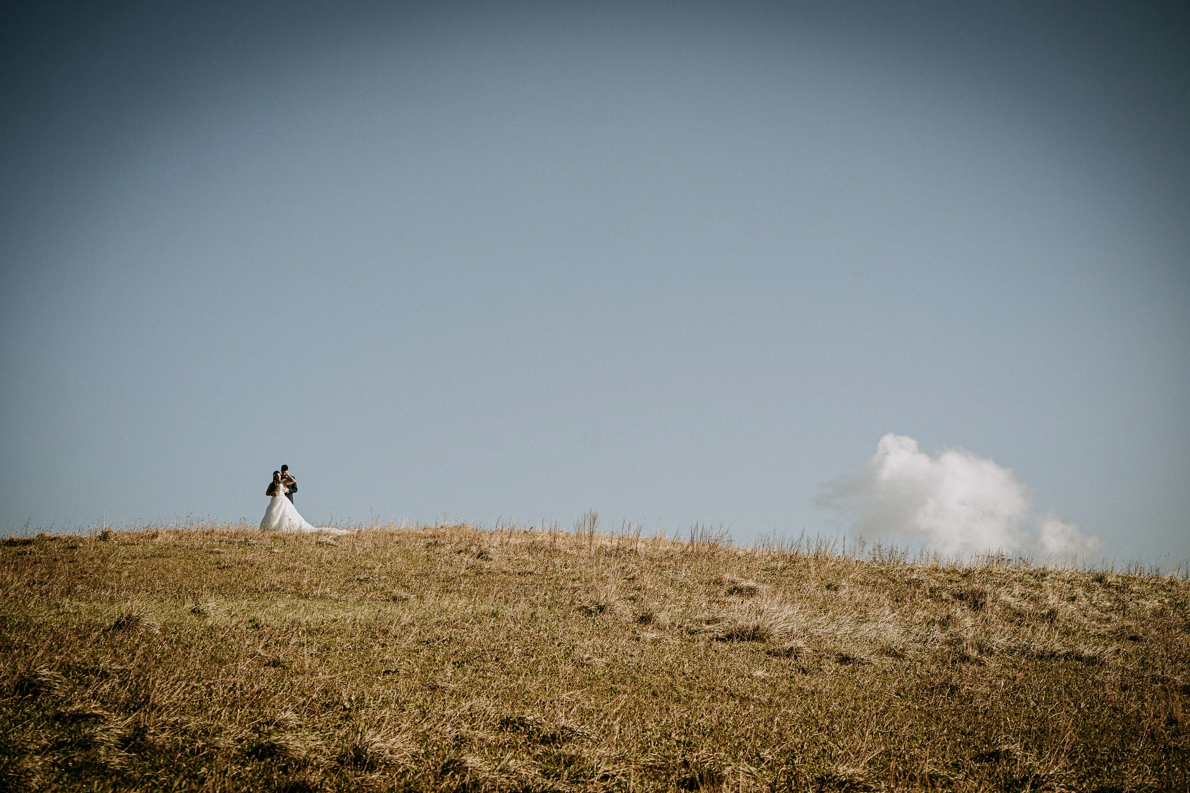 Novia sola en la cima de una colina costera durante una sesión de postboda en El Molino, cerca de Llanes, Asturias.