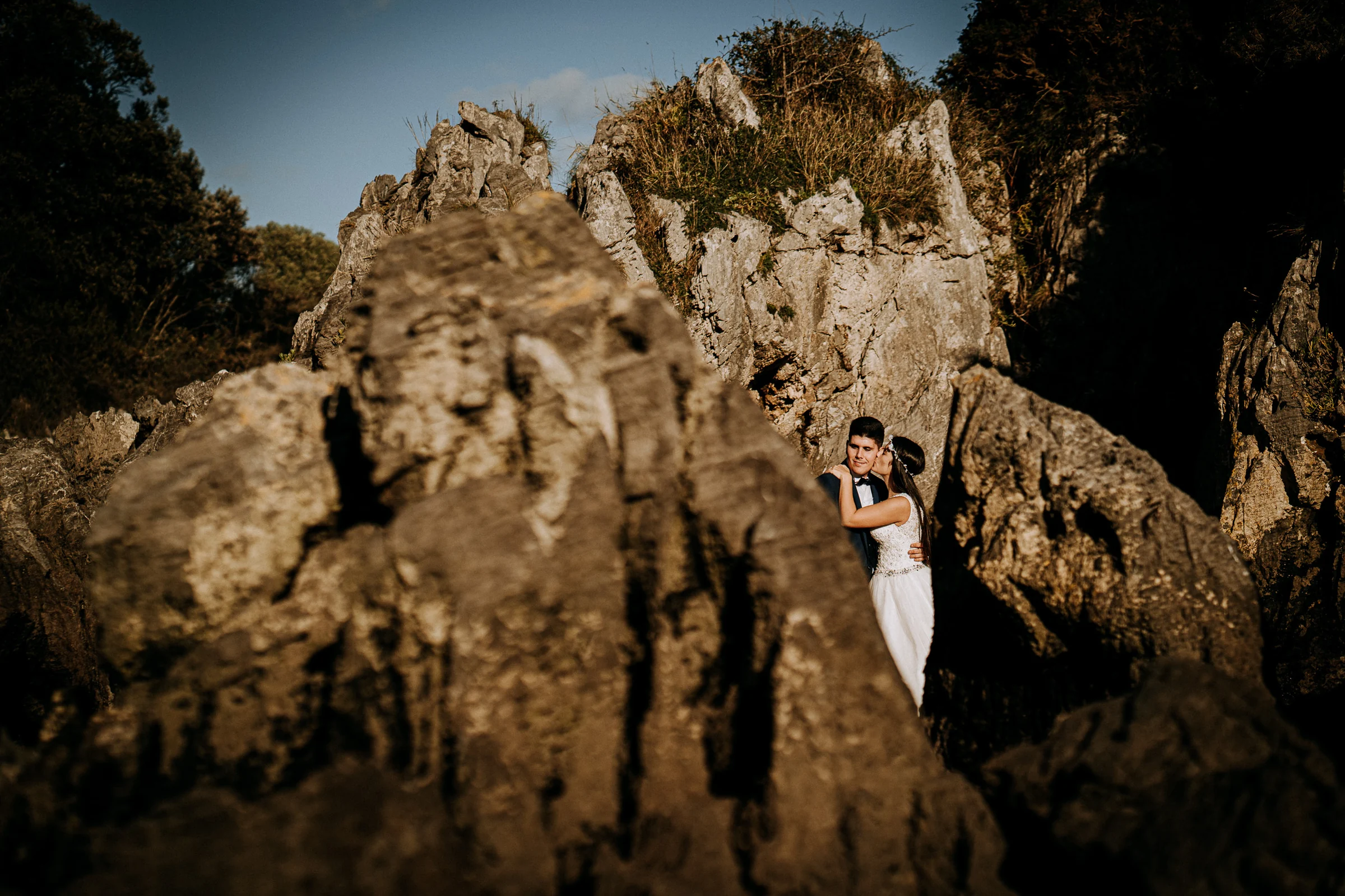 Pareja abrazada entre formaciones rocosas durante una sesión de postboda en El Molino, cerca de Llanes, Asturias.