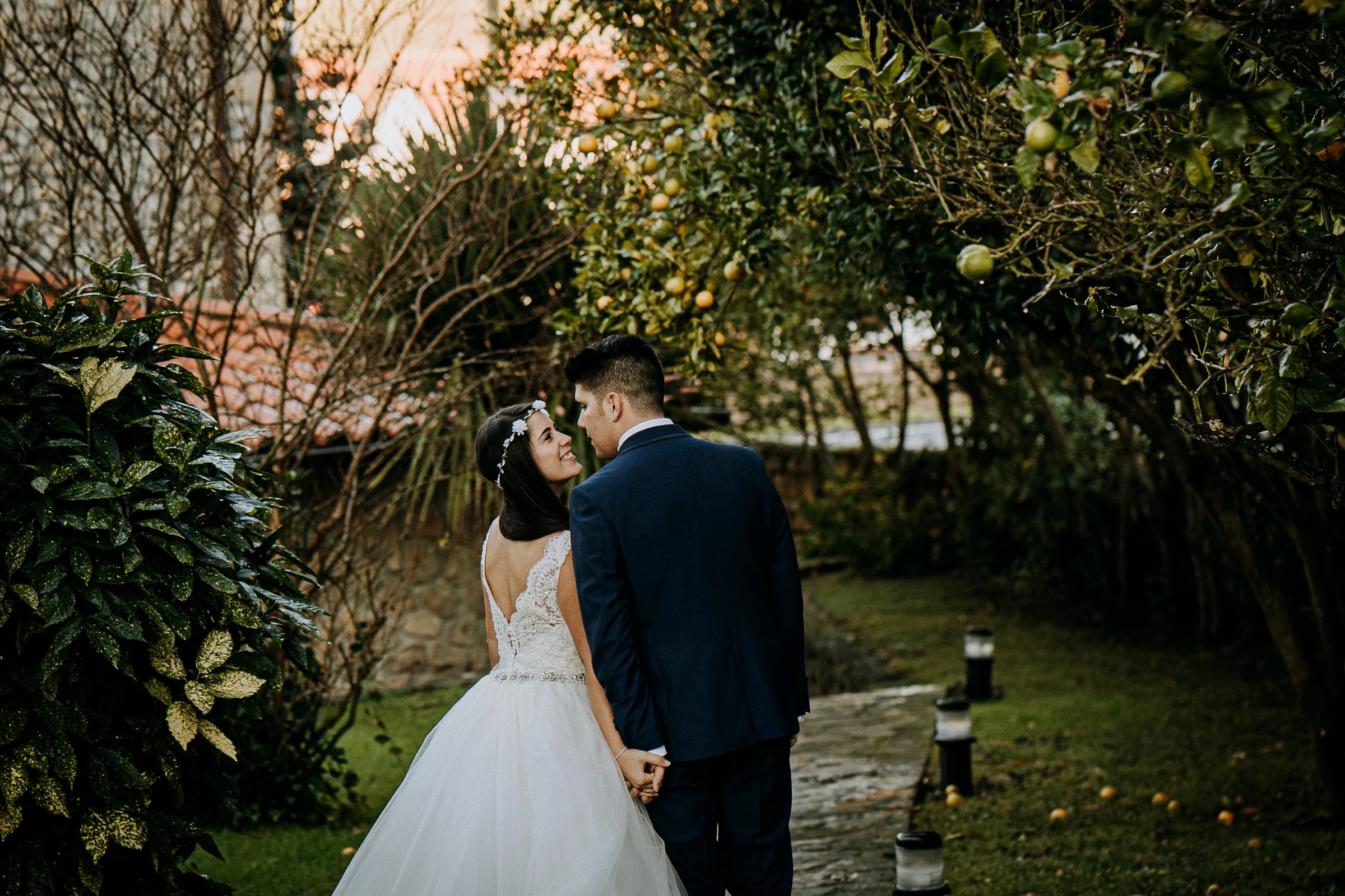 Pareja caminando de la mano por un jardín durante una sesión de postboda en El Molino, cerca de Llanes, Asturias.
