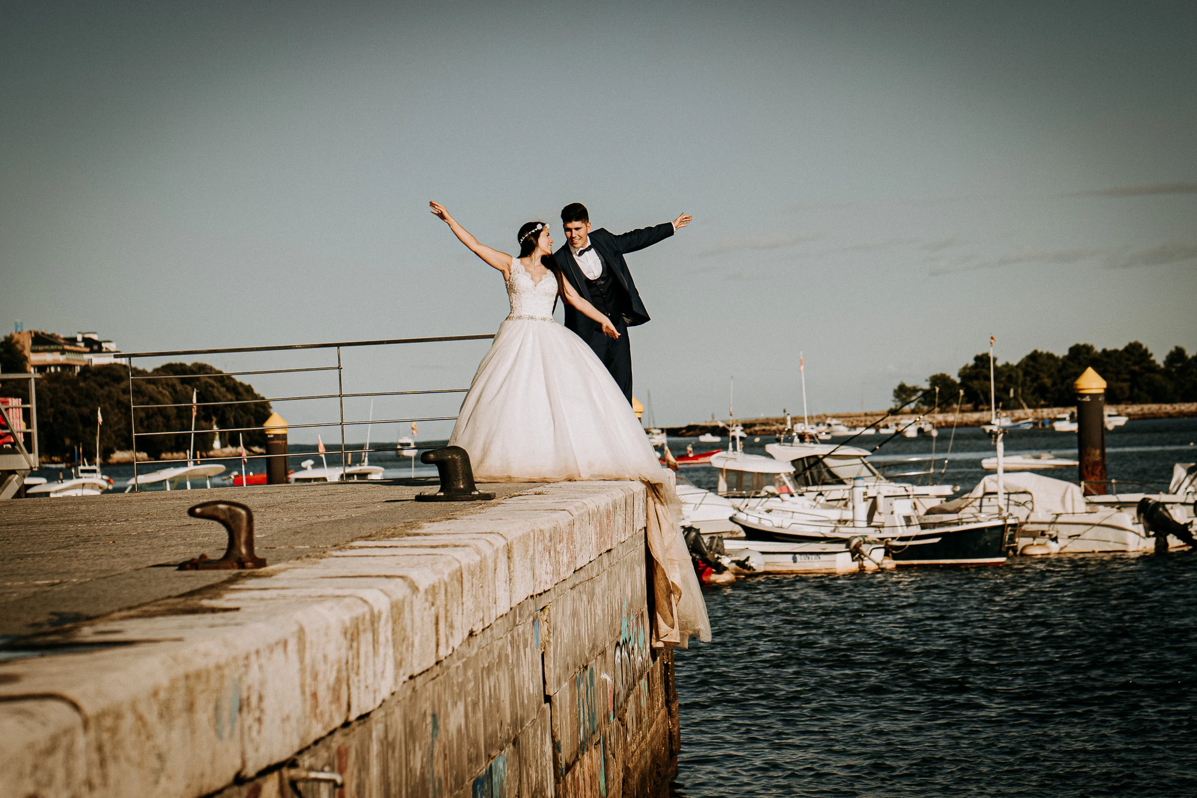 Pareja celebrando junto a un pequeño puerto pesquero durante una sesión de postboda en El Molino, cerca de Llanes, Asturias.